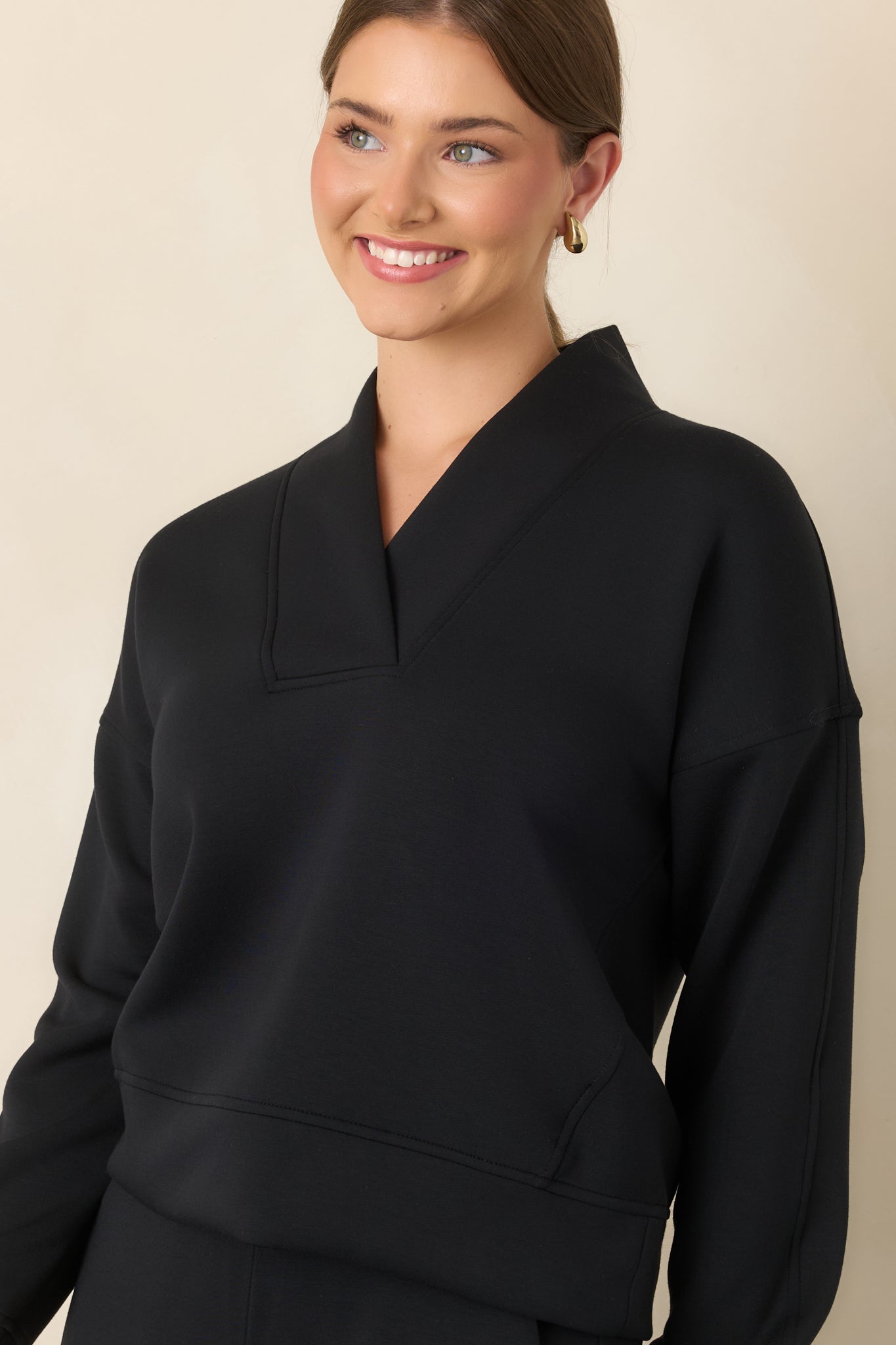 Detailed view of the structured V-neckline framed by a wide collar and relaxed shoulder construction.