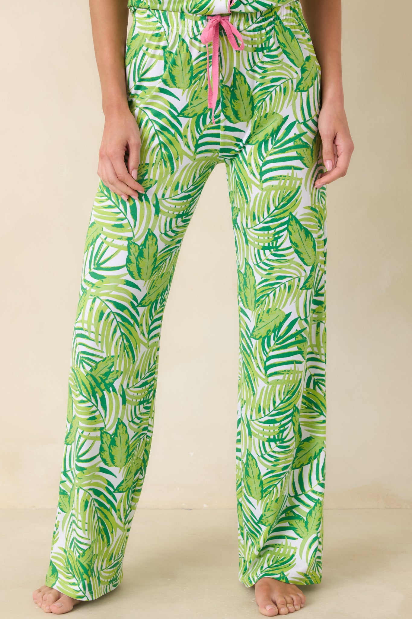 Cropped view of tropical print pants highlighting elastic waistband, drawstring tie, and side pockets