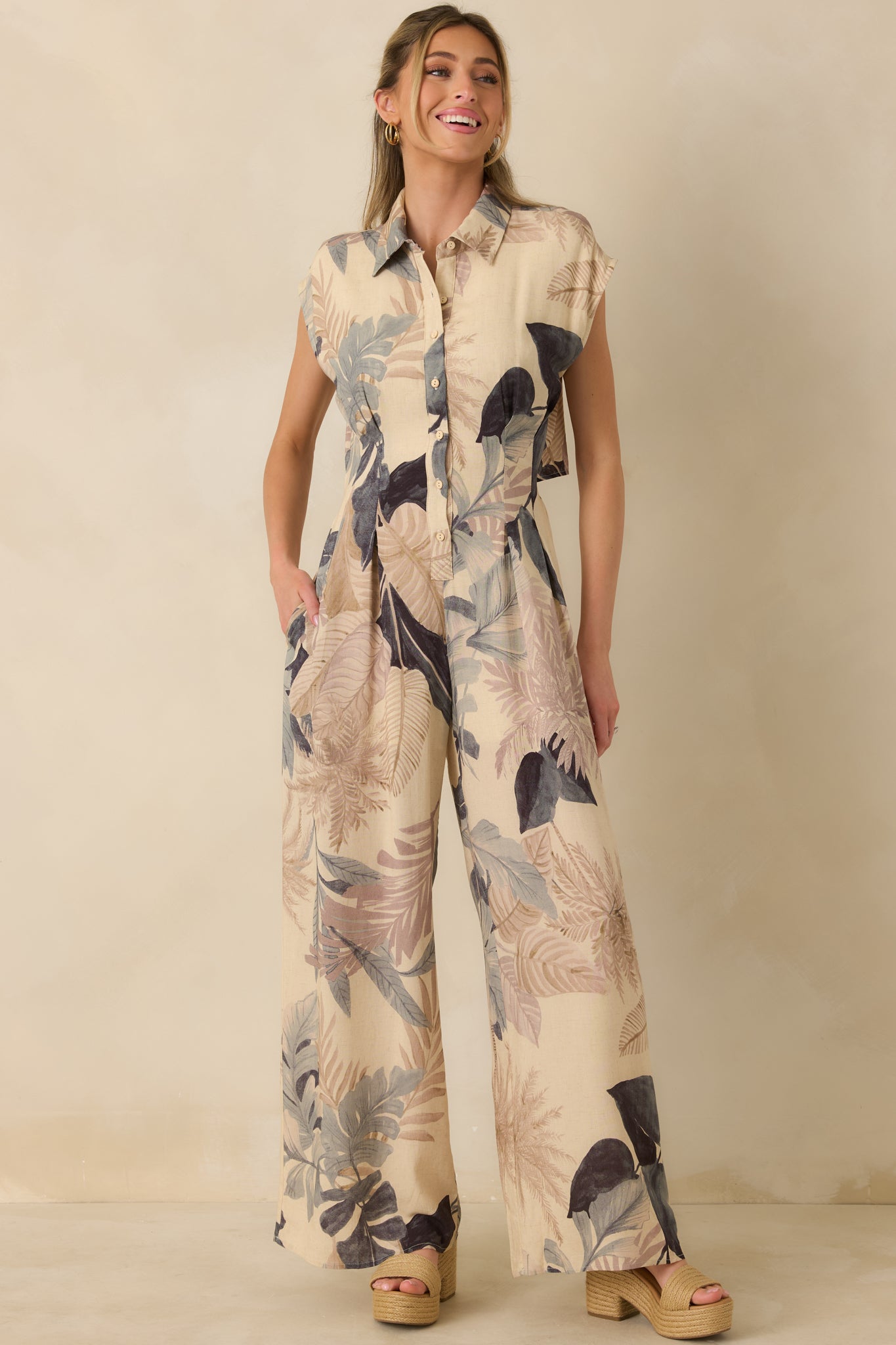 Tropical print wide-leg jumpsuit in beige with collared neckline and tailored button-front bodice.