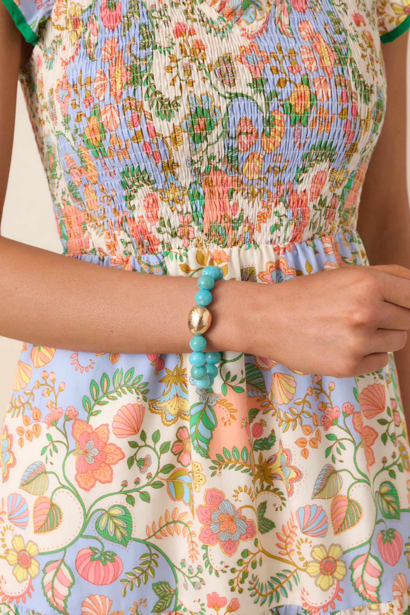 Turquoise stretch bracelet with smooth round beads and a central polished gold-tone accent bead.