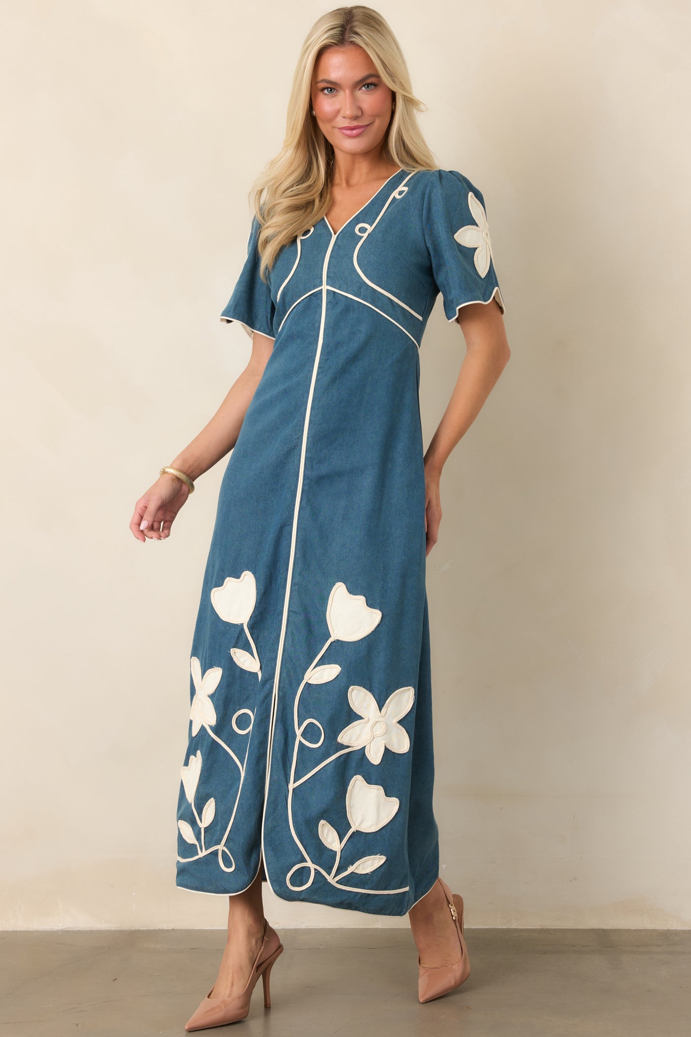 V-neck maxi dress designed with short sleeves, floral appliqué detailing, a sculpted waist, and graceful full-length skirt.