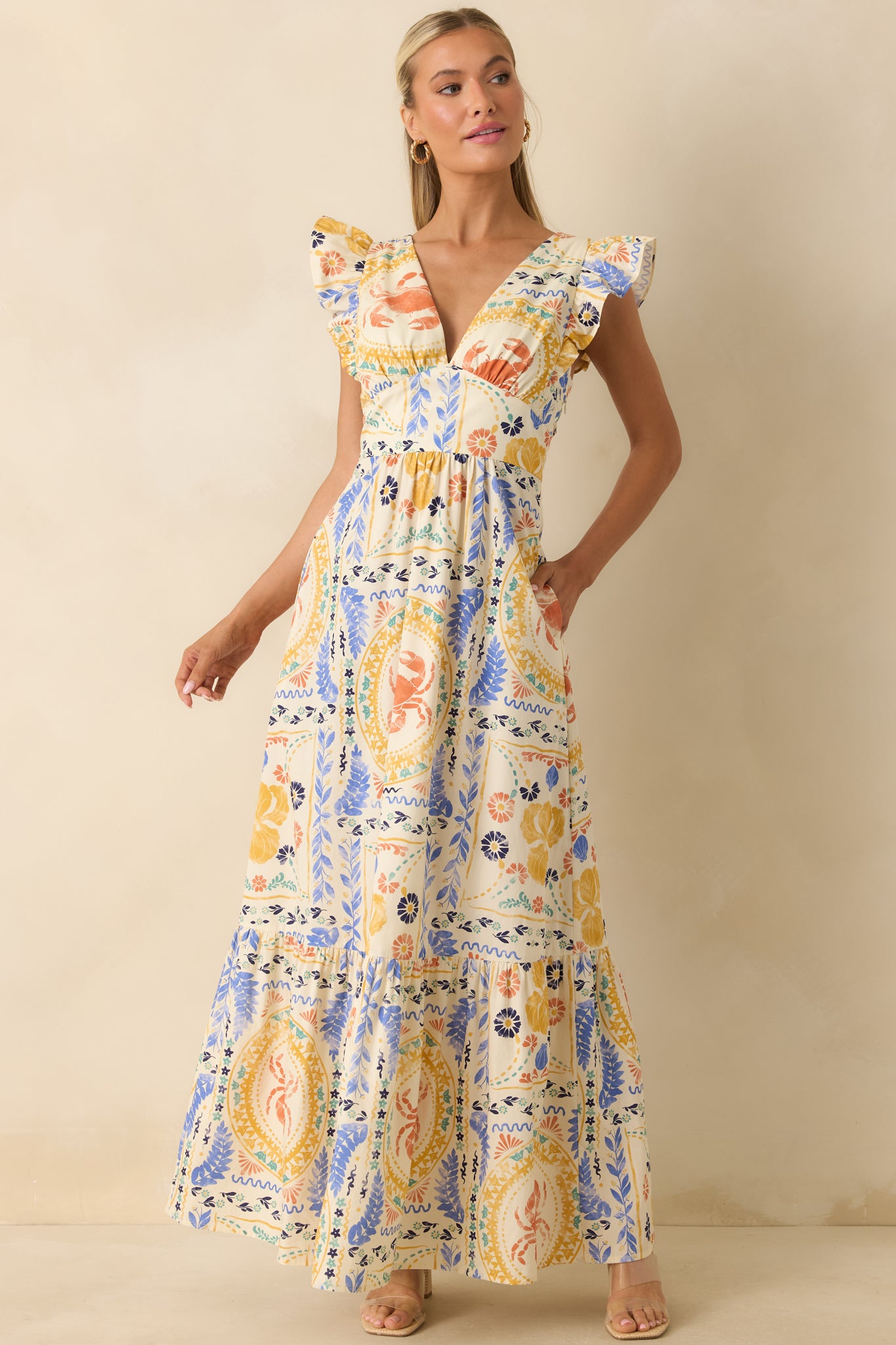Colorful maxi dress designed with a flattering V-neckline, ruffled cap sleeves, a fitted bodice, and graceful tiered movement.