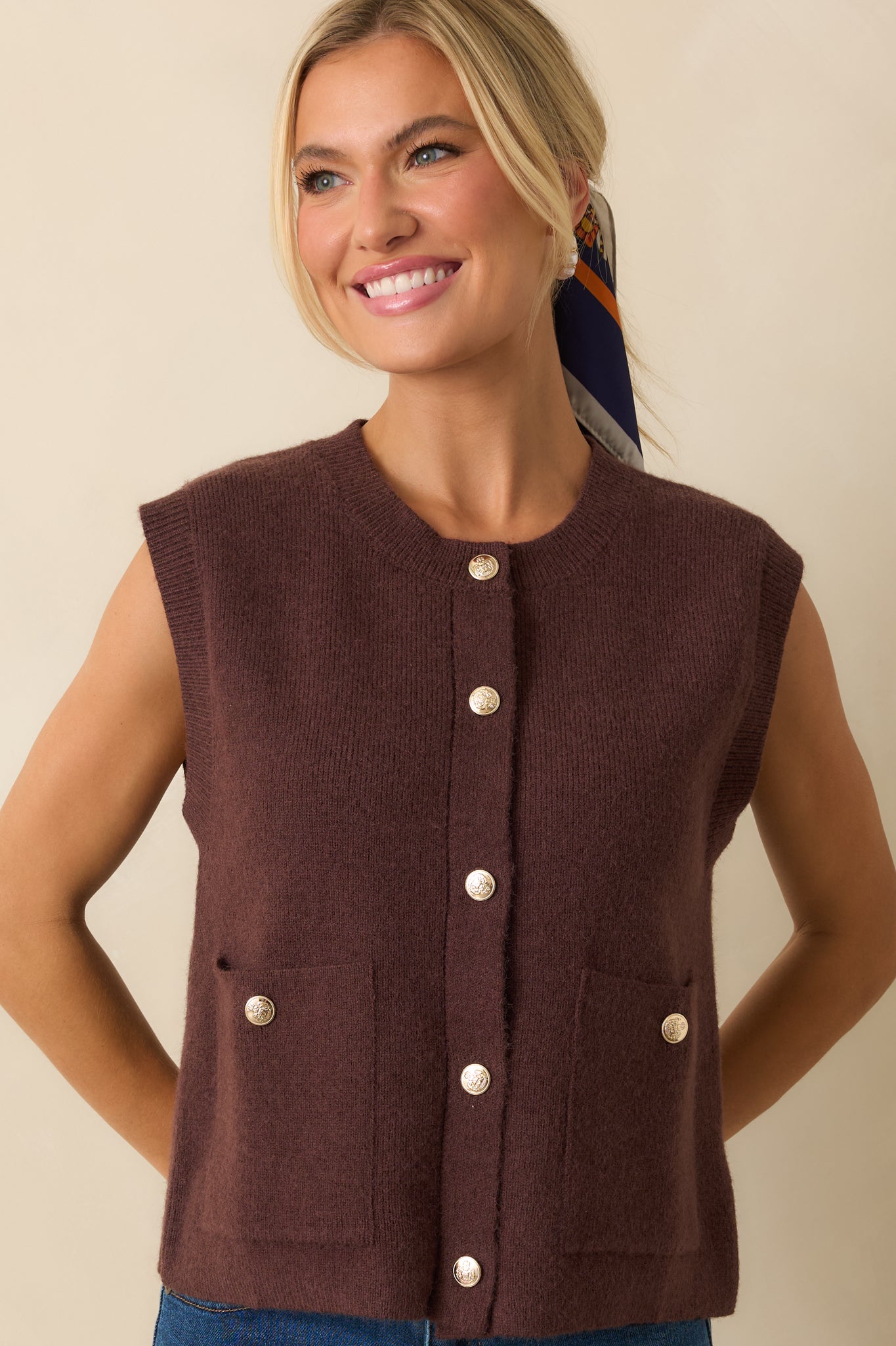 Focus on the lower portion of the vest, showing the texture of the knit and gold button accents.