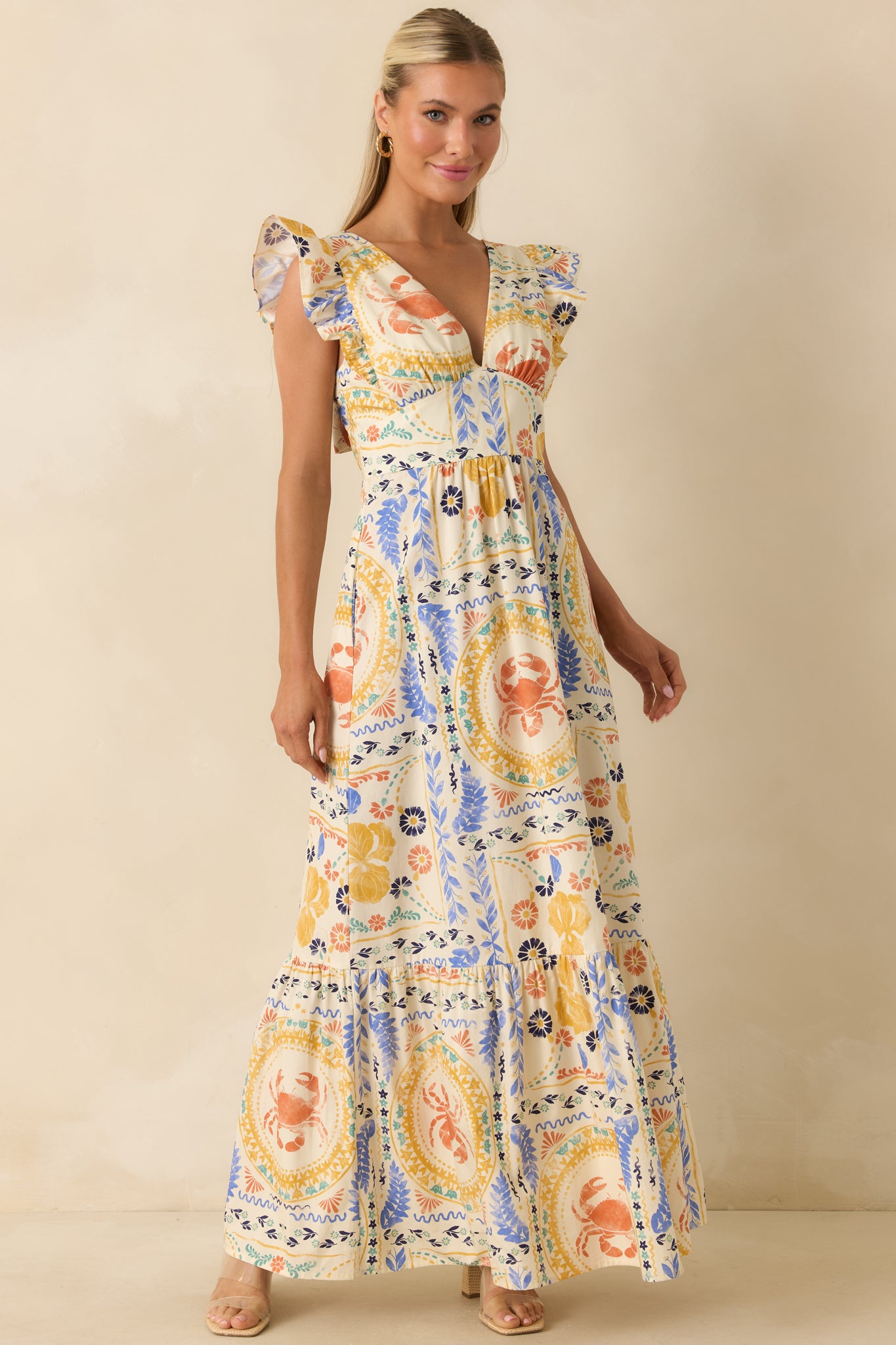 Vibrant maxi dress with Mediterranean-inspired patchwork, ruffled cap sleeves, a fitted bodice, and a flowing tiered skirt.