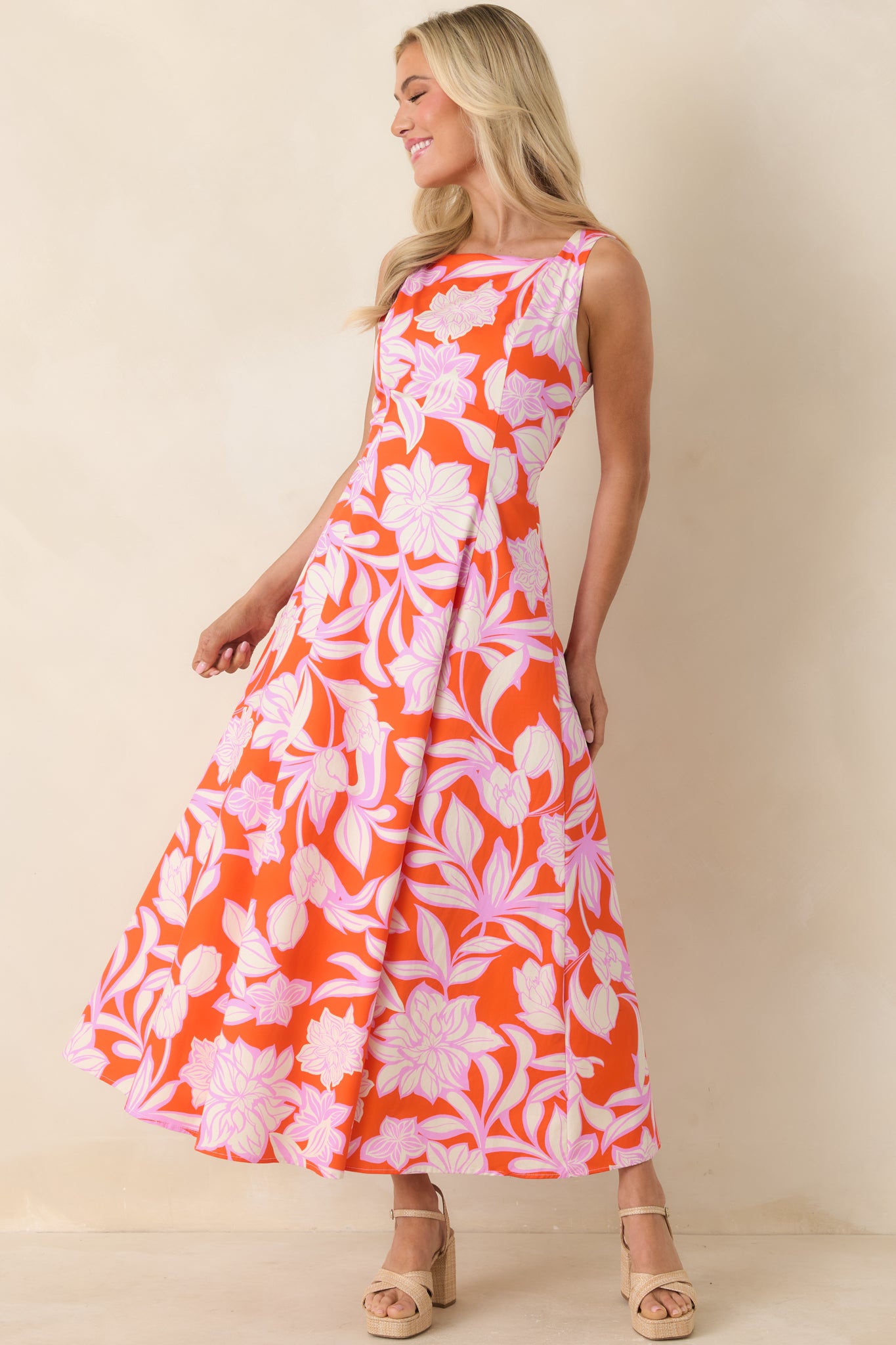 Vibrant orange maxi dress featuring soft orchid pink florals and graceful skirt.