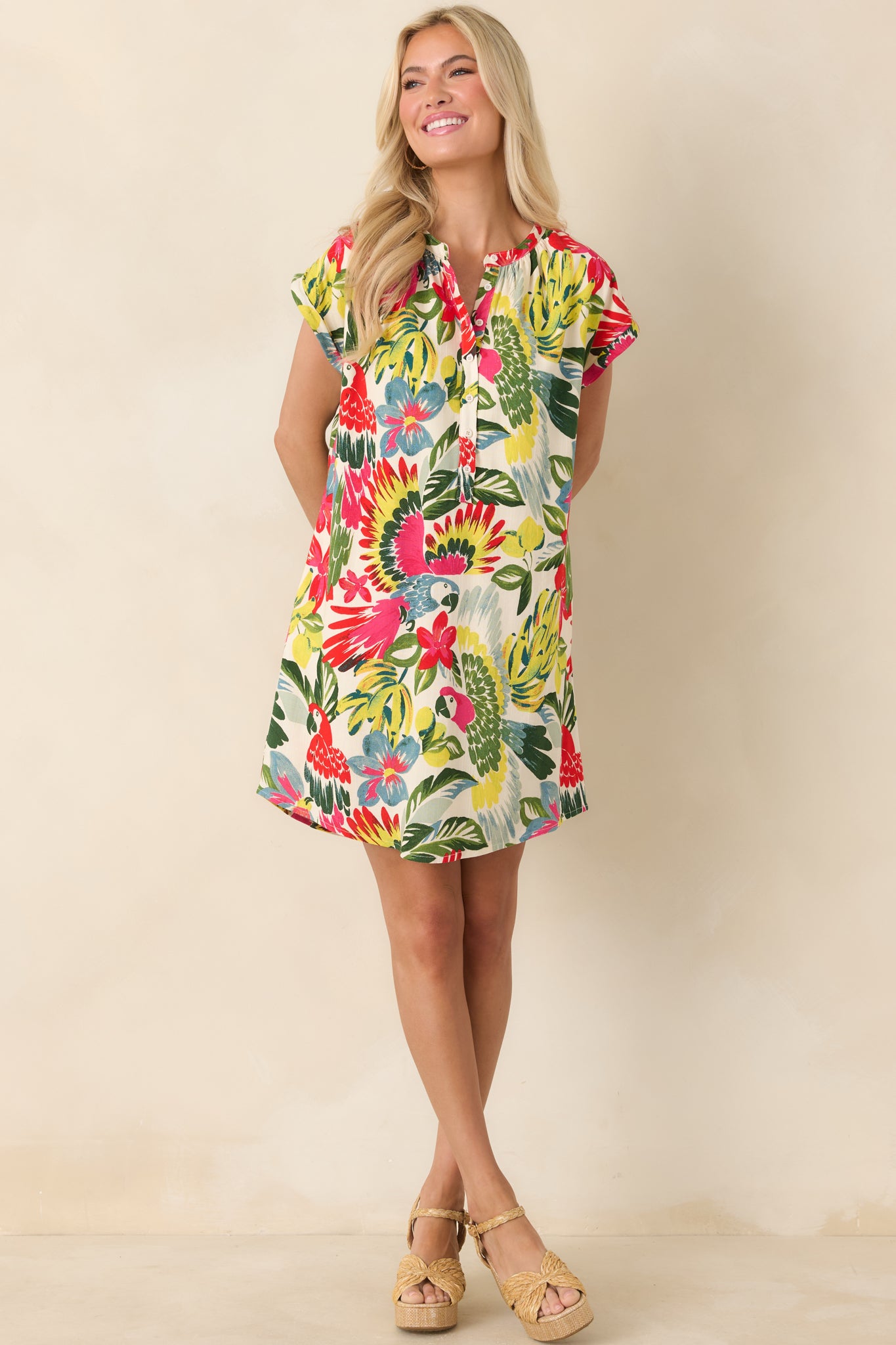 Vibrant parrot-print mini dress featuring cap sleeves, lightweight drape, and hidden side pockets