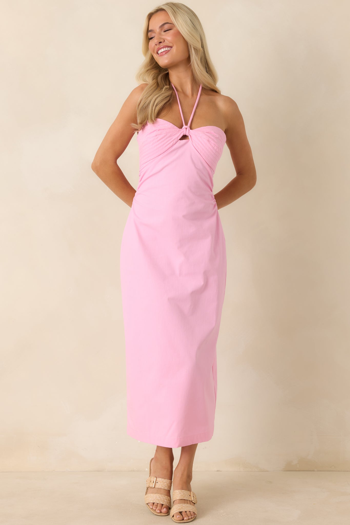 Vibrant pink halter dress with sculpted waist detailing and an elegant midi-length silhouette.