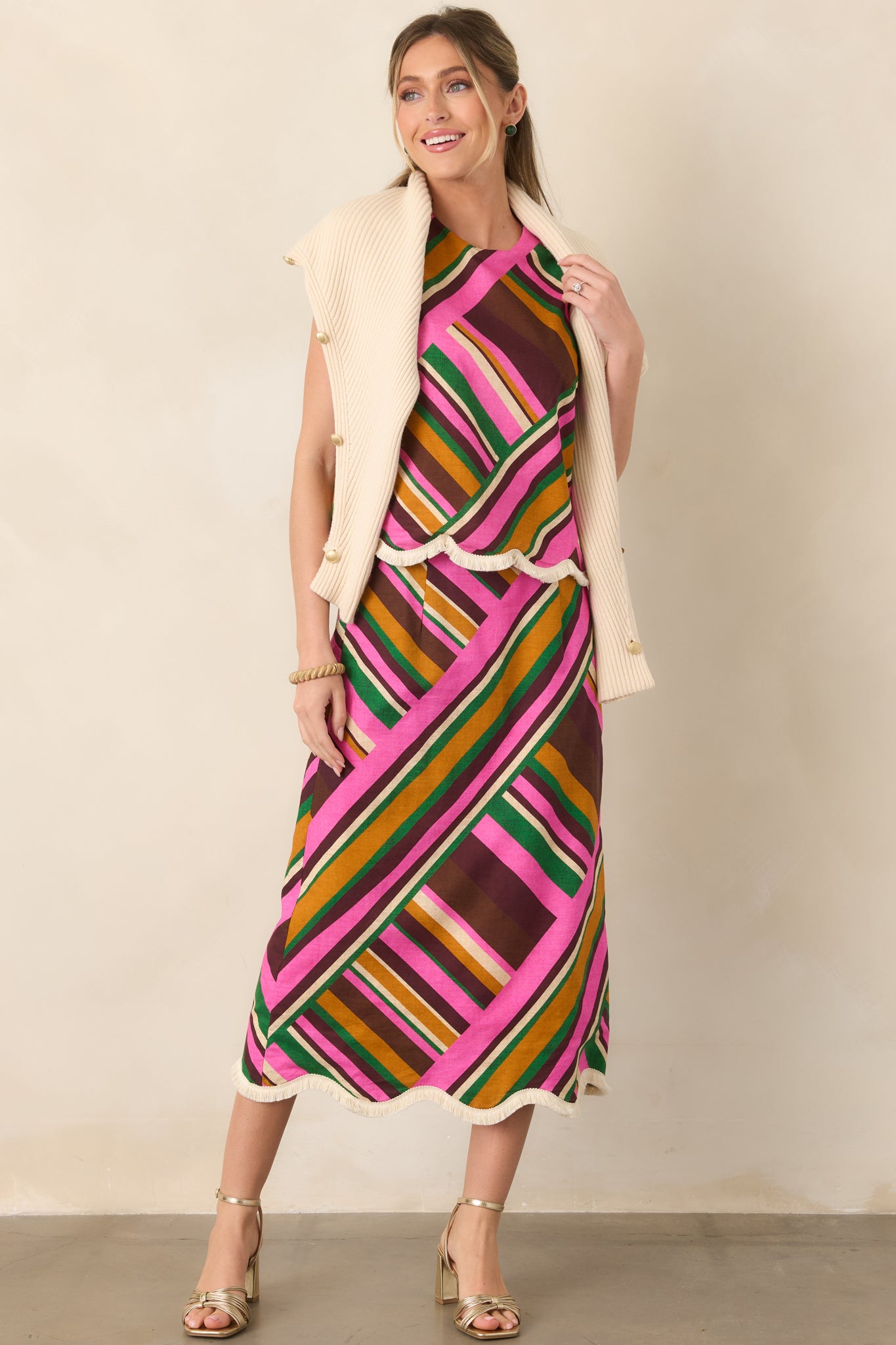 Vibrant pink multi stripe top with an easy sleeveless silhouette, clean round neckline, and textured scalloped hem.