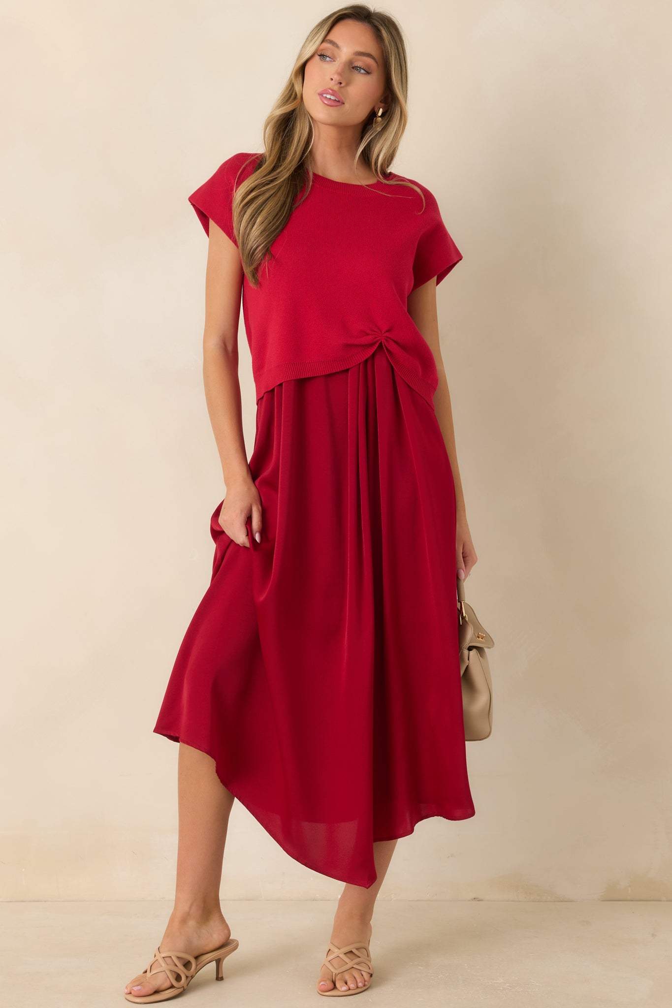 Vibrant red knit top showcasing cap sleeves and a unique cinched front accent that adds shape to the silhouette.