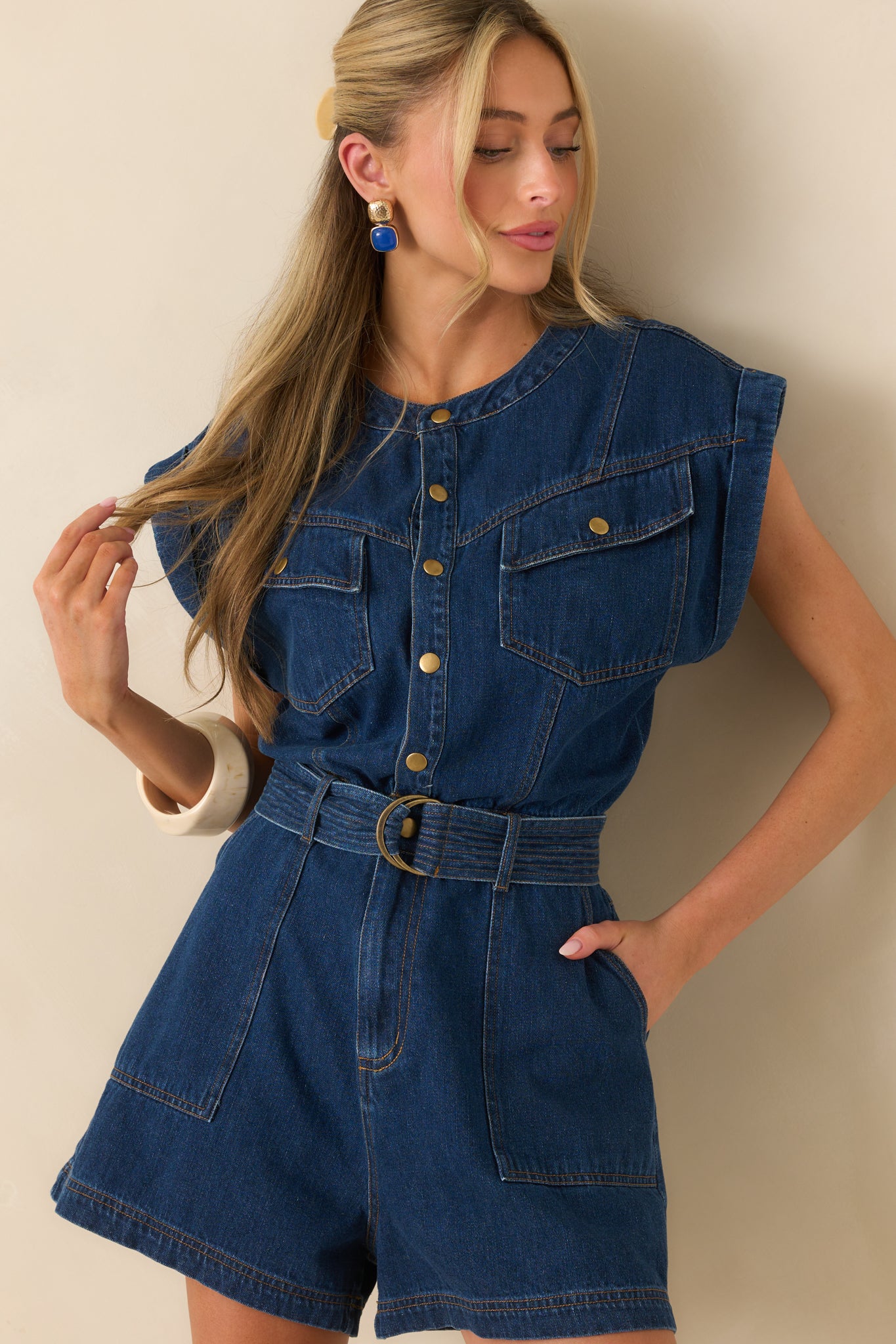 A cropped view focusing on the button front placket and cap sleeve detail of the denim romper.