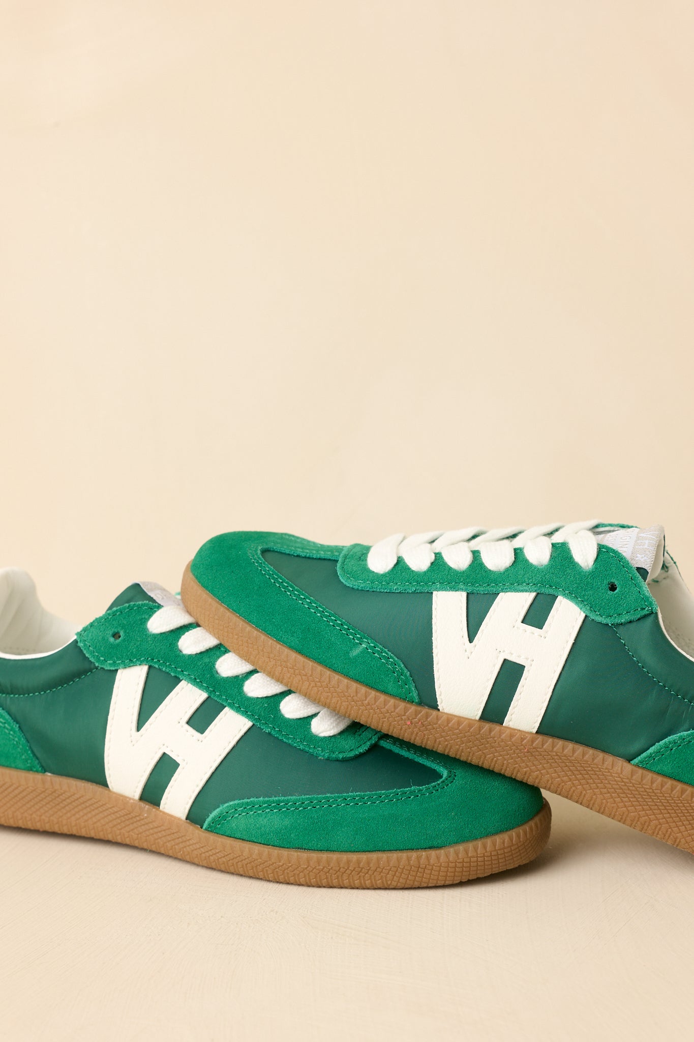 Beige background view highlighting the sneaker’s side profile with suede overlays and structured leather accents.