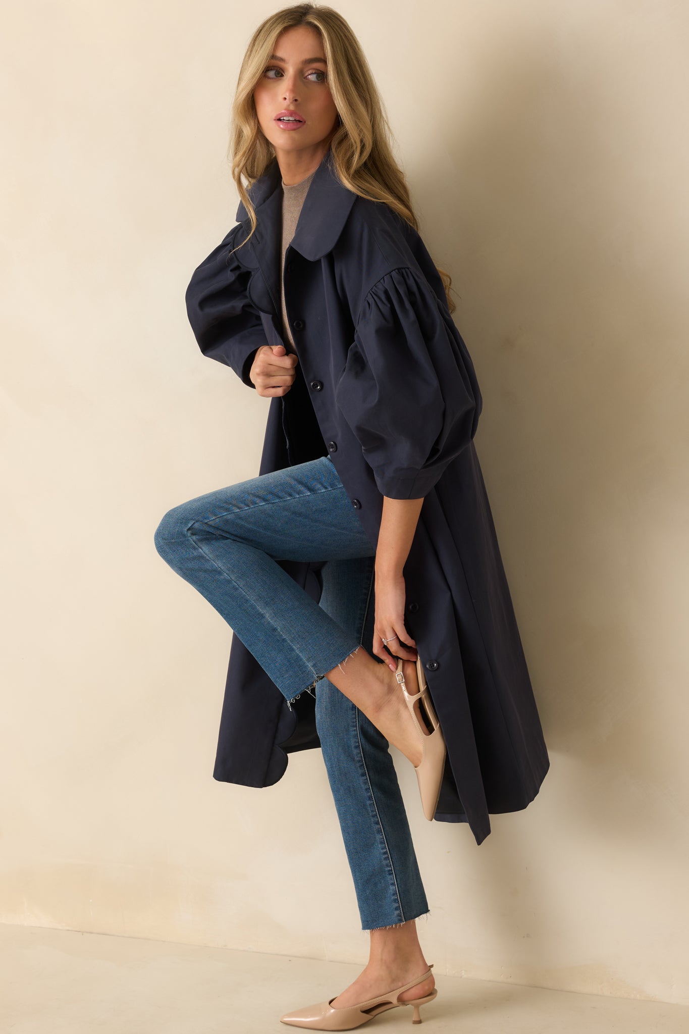 View of the puff sleeves with gathered shoulders and scalloped trim along the navy coat.