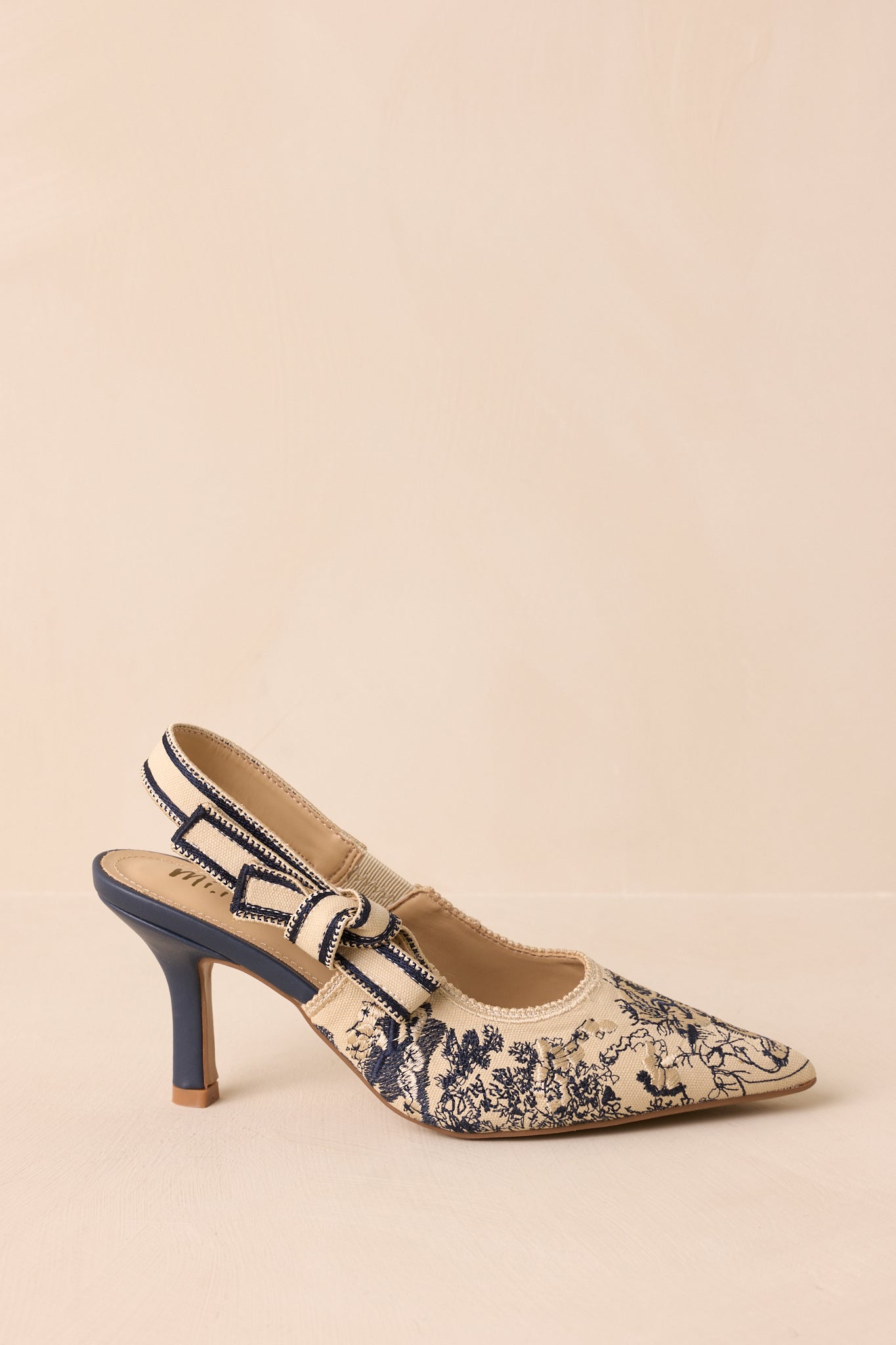 Angled beige background view showcasing the smooth sole and refined heel profile.