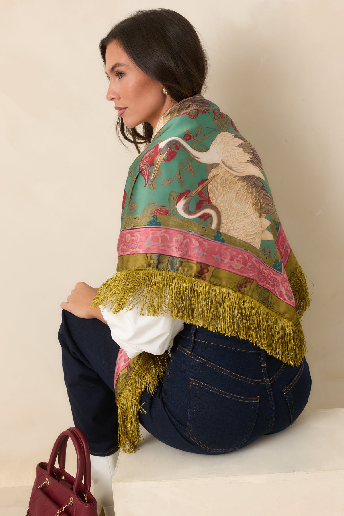 Vintage-inspired printed item showcasing cranes, red flowers, olive foliage, and long golden olive fringe.