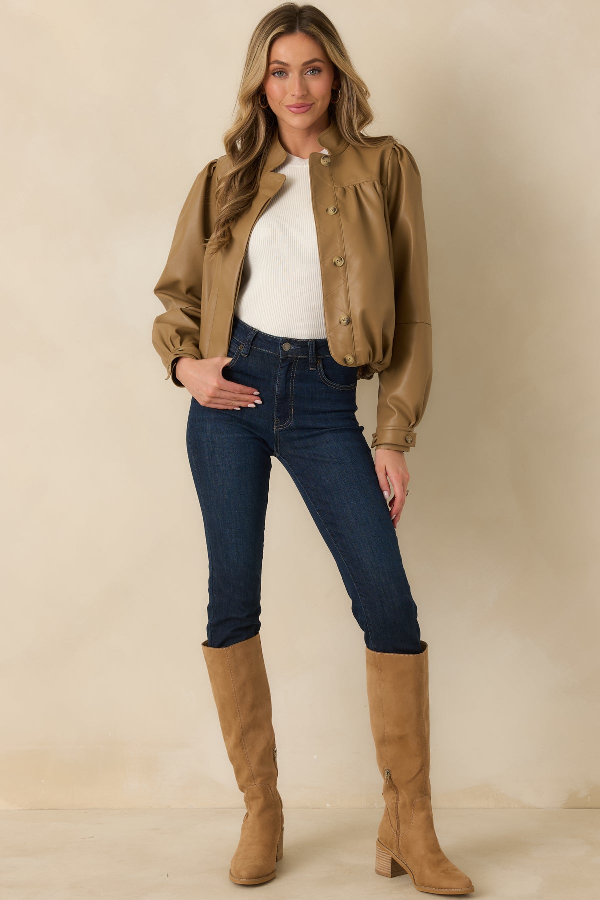 Waist-length vegan leather jacket combining gathered yoke detailing, voluminous puff sleeves, buttoned cuffs, and a softly defined hem.