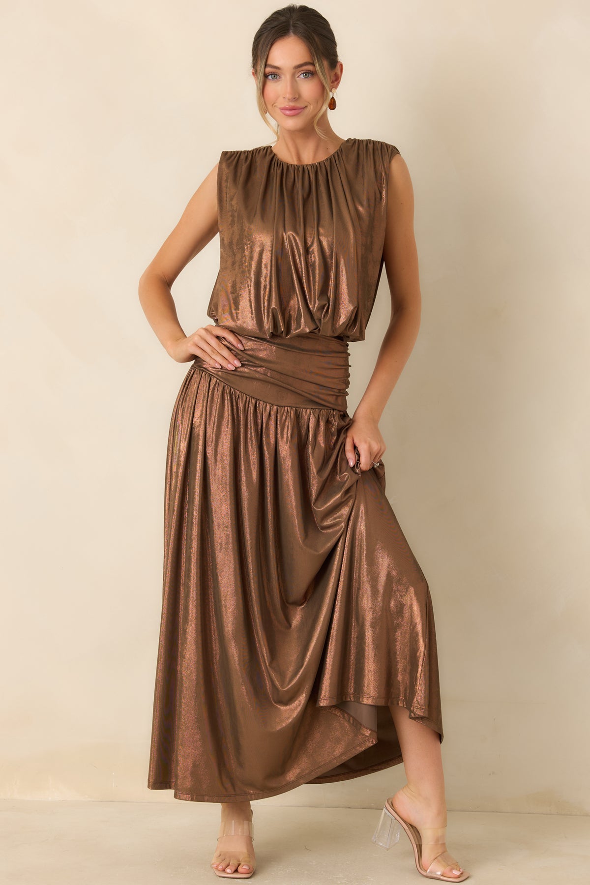 Warm bronze skirt featuring a fitted upper hip, gathered fabric, and a voluminous maxi-length hem.