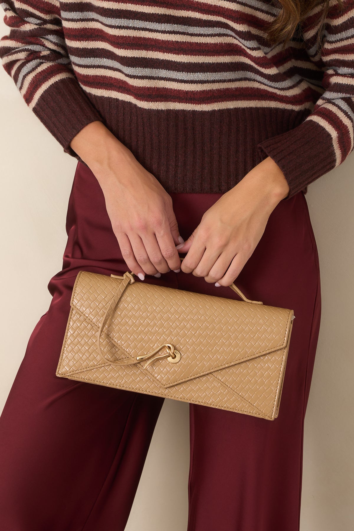 Warm honey-tan clutch showcasing textured woven faux leather and sculptural gold-tone hardware.