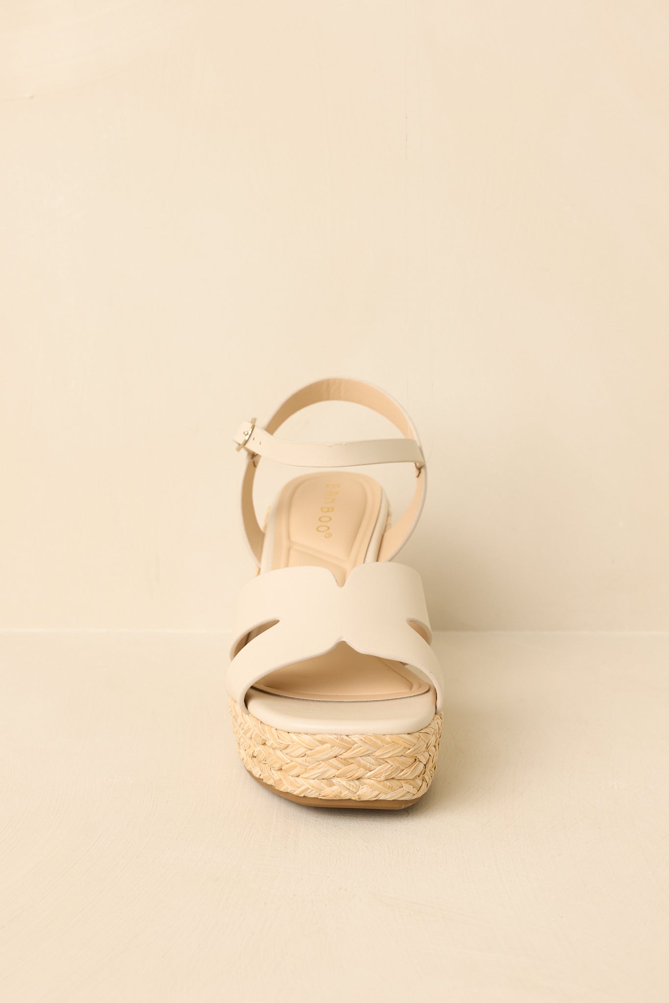 Wedge sandals displayed from a straight-on angle showcasing the ivory straps and woven platform silhouette.