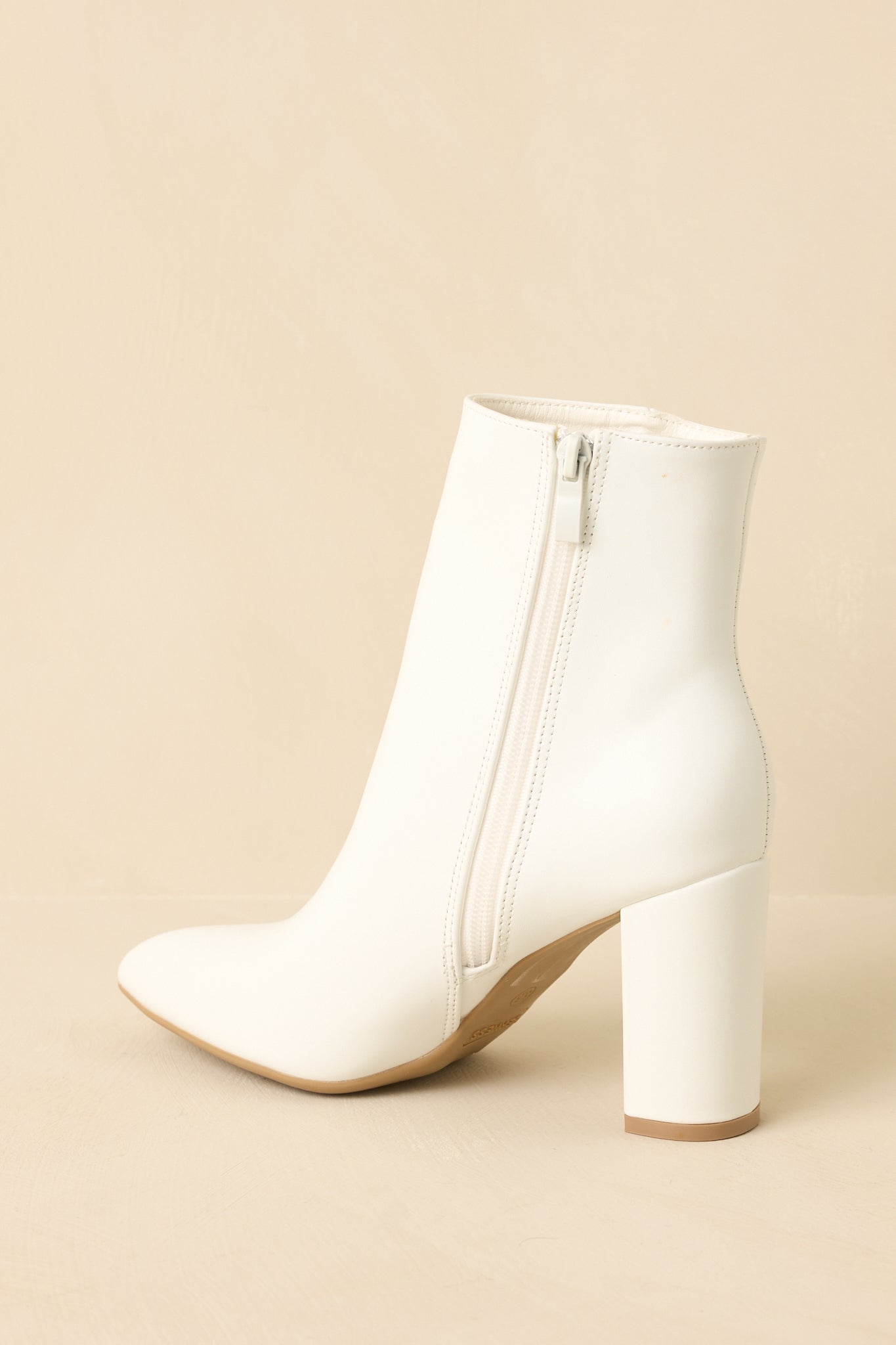 White ankle boots angled to emphasize the heel height and modern profile.