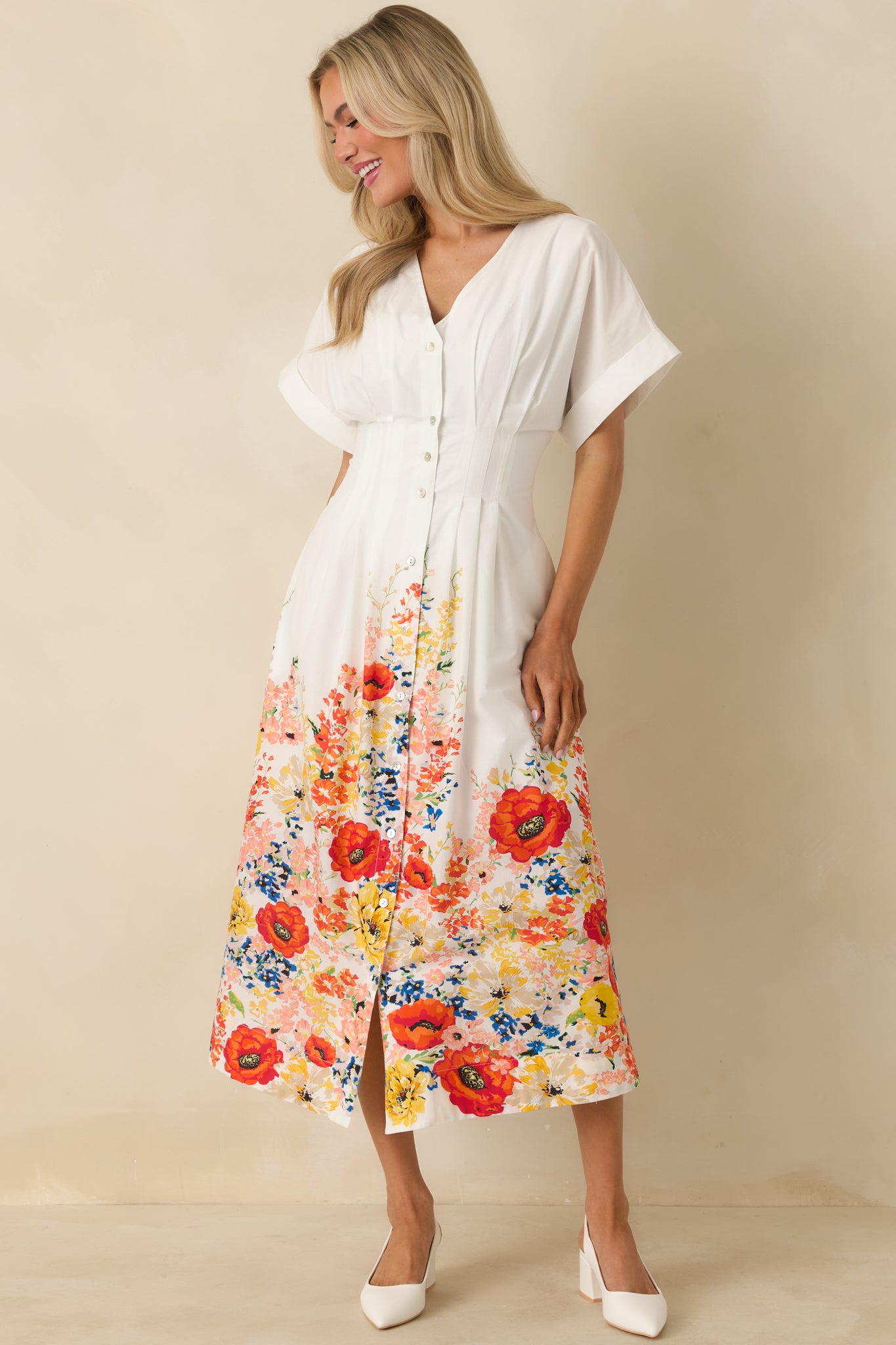 White button-down midi dress with a V-neckline, flutter sleeves, and a vibrant floral border adding contrast at the hem.