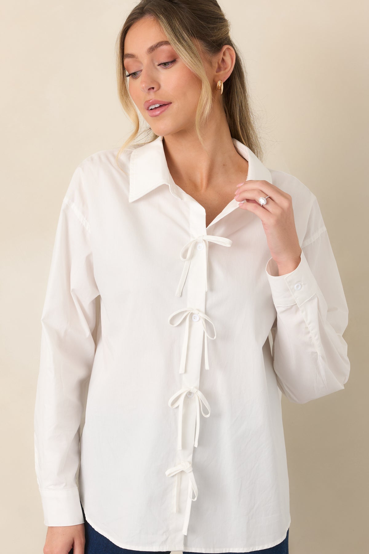 Front detail of the white button-front top emphasizing the neat collar, evenly spaced buttons, and decorative bow details.