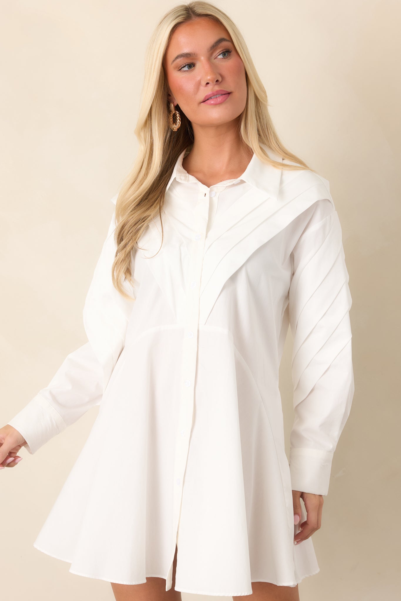 Detailed view of the white woven cotton fabric and button-front bodice, accented by structured pleated panels along the yoke.