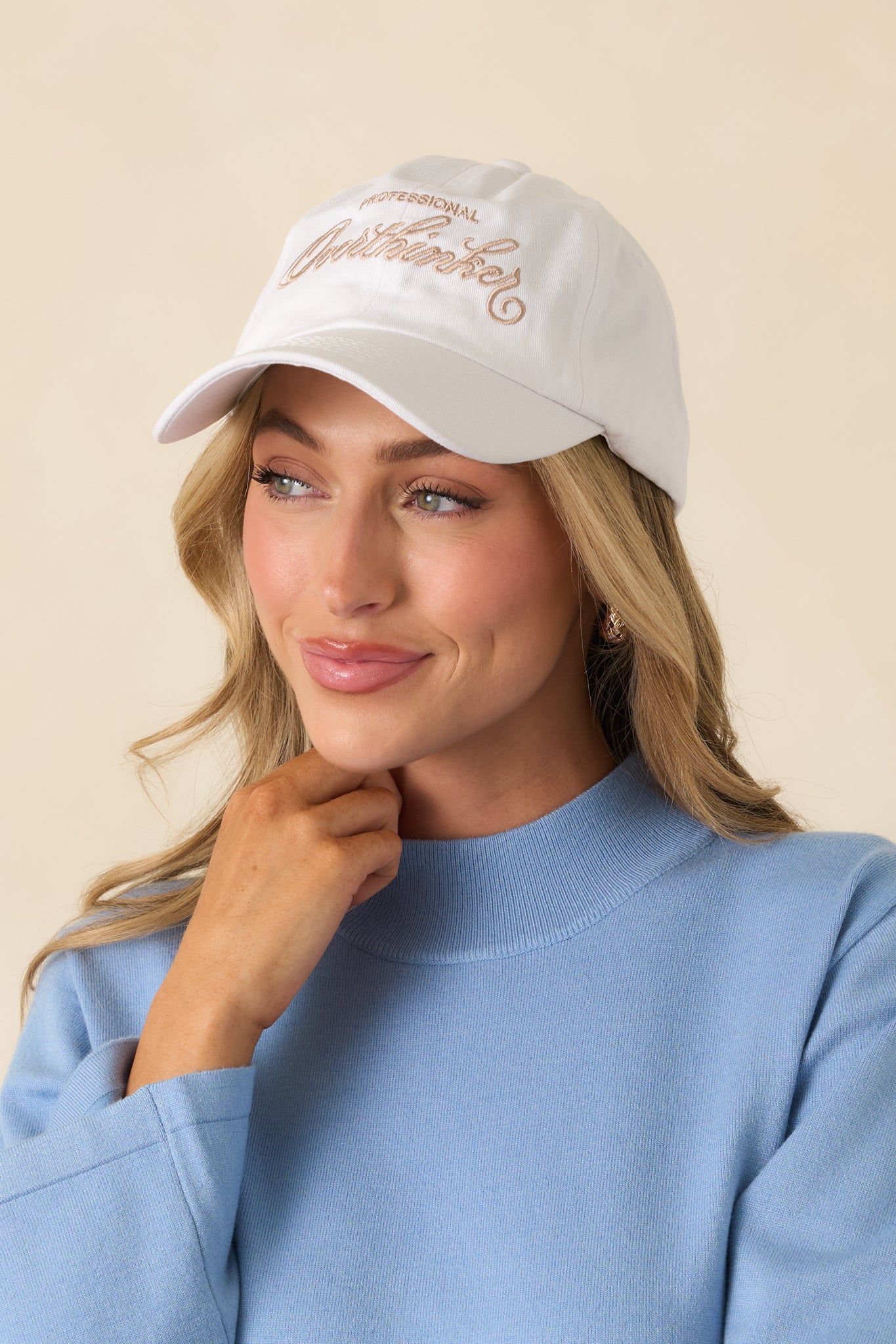 White cotton cap showing the curved brim shape and clean, minimalist stitching around the crown.