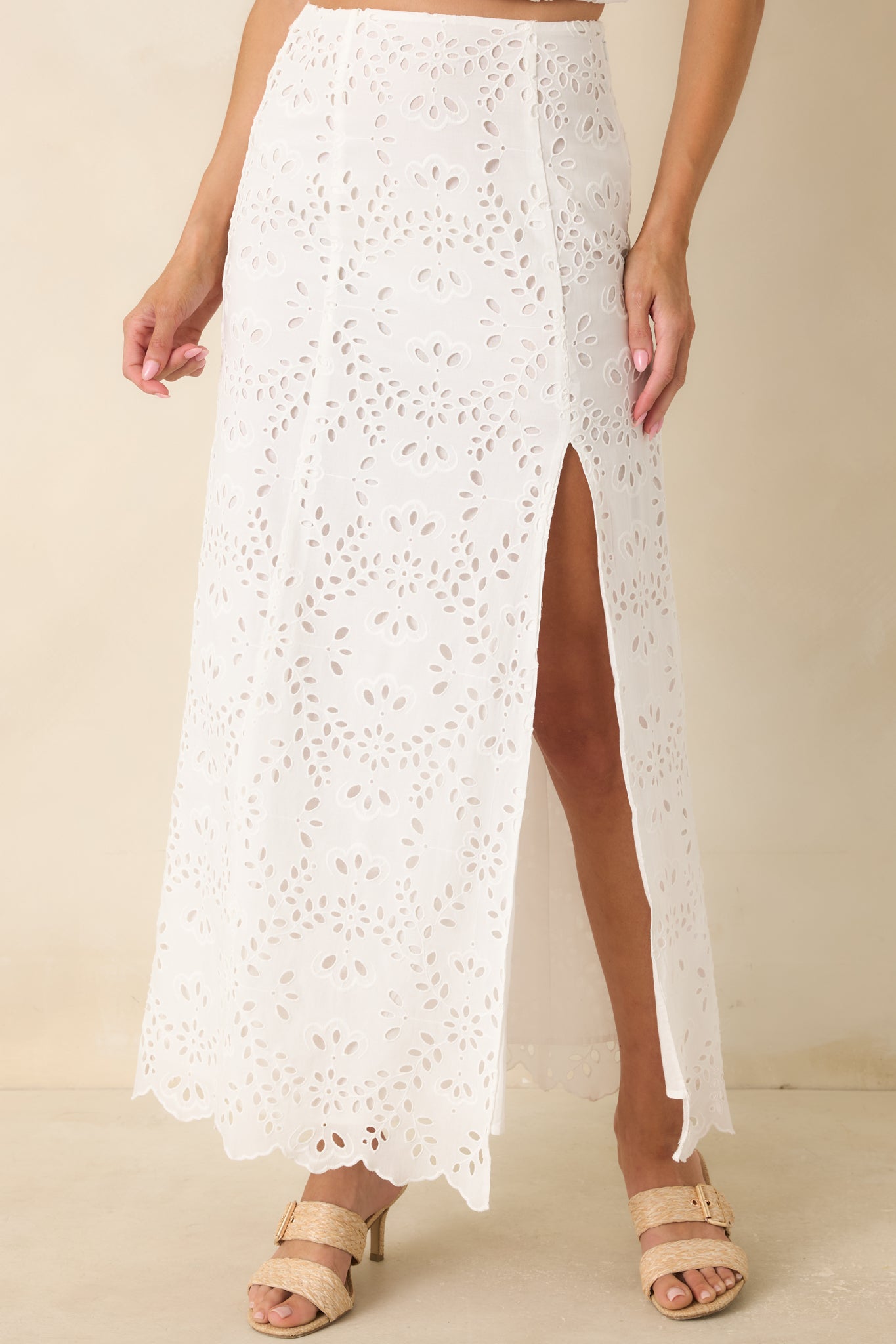 White cotton eyelet skirt highlighting the high-rise waistband and detailed floral embroidery across the fabric.