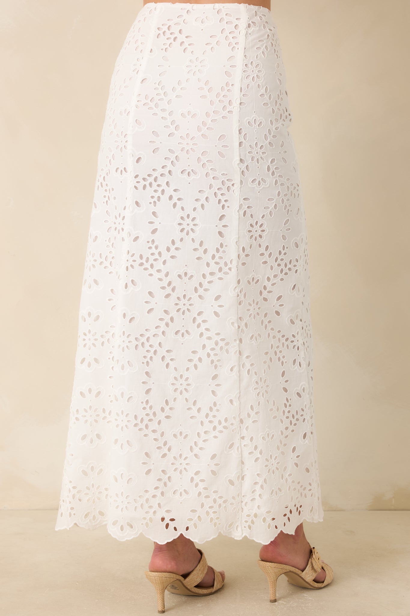 White cotton eyelet maxi skirt from the back, featuring a clean high-rise silhouette with continuous floral embroidery and a smooth, flowing shape.