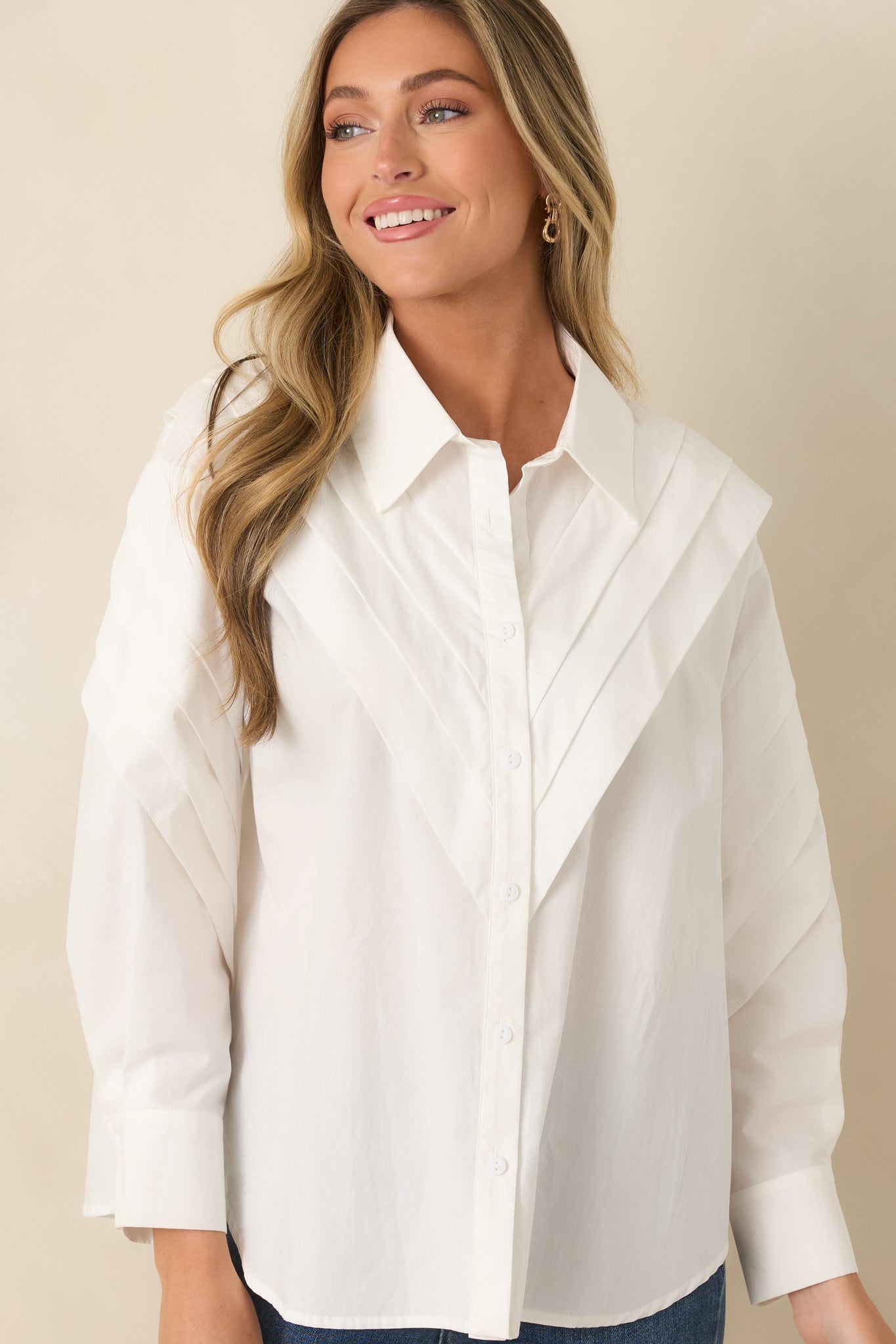 White top showcasing the sculptural pleating, smooth cotton texture, and refined button details.