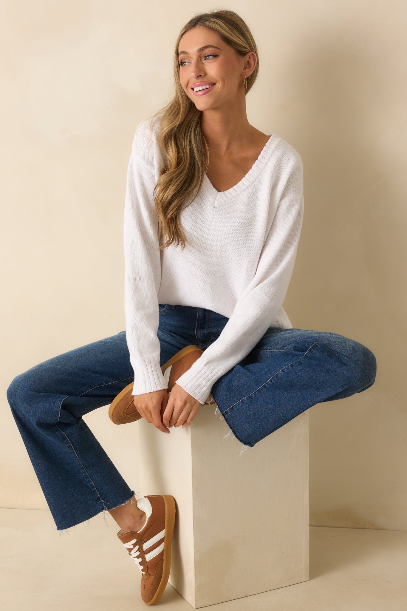 White 100% cotton sweater with v-neckline, long drop shoulder sleeves, relaxed fit, and ribbed hem.