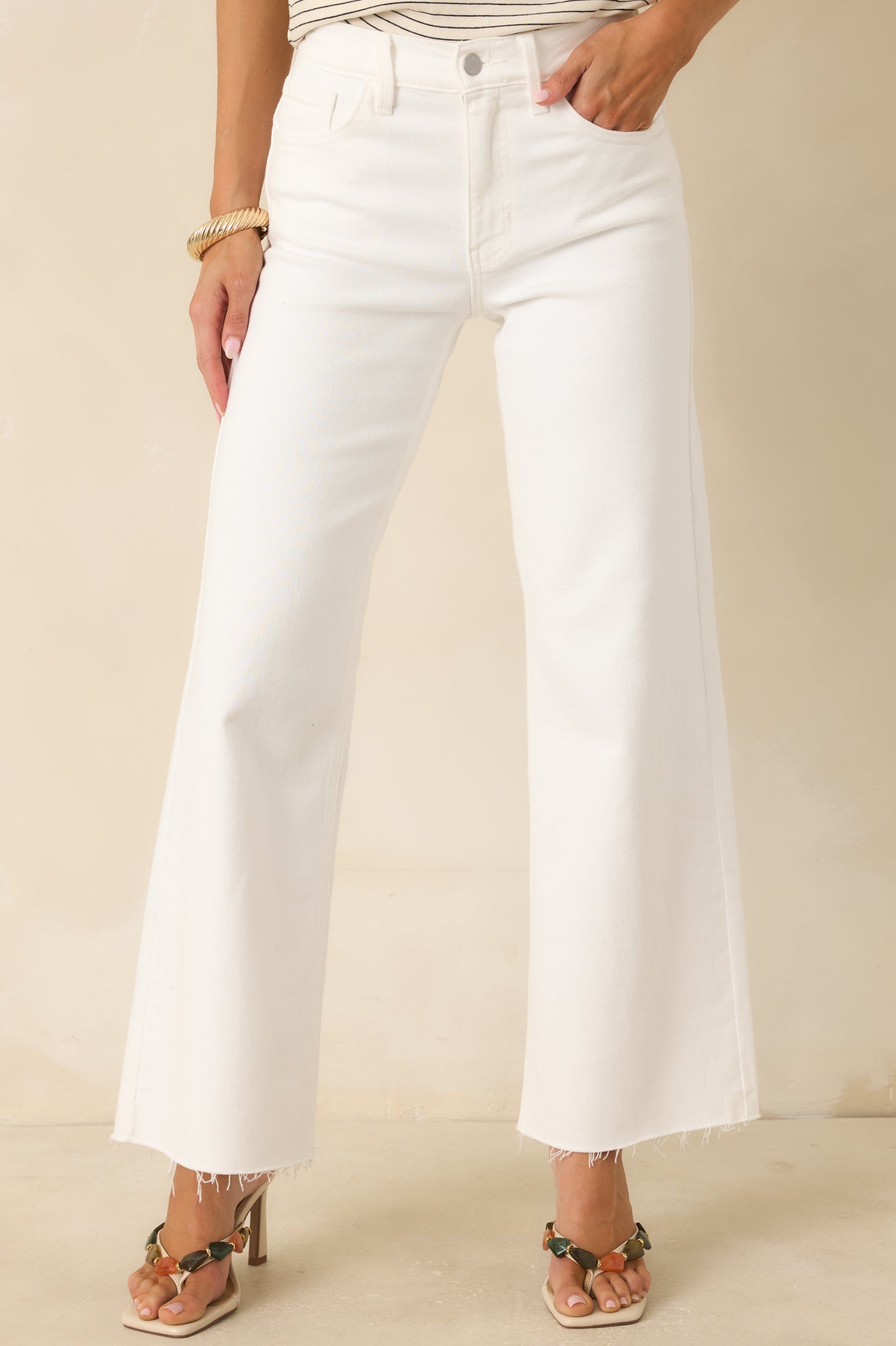 White denim pants featuring a structured waist, classic five-pocket styling, and raw-cut hems.
