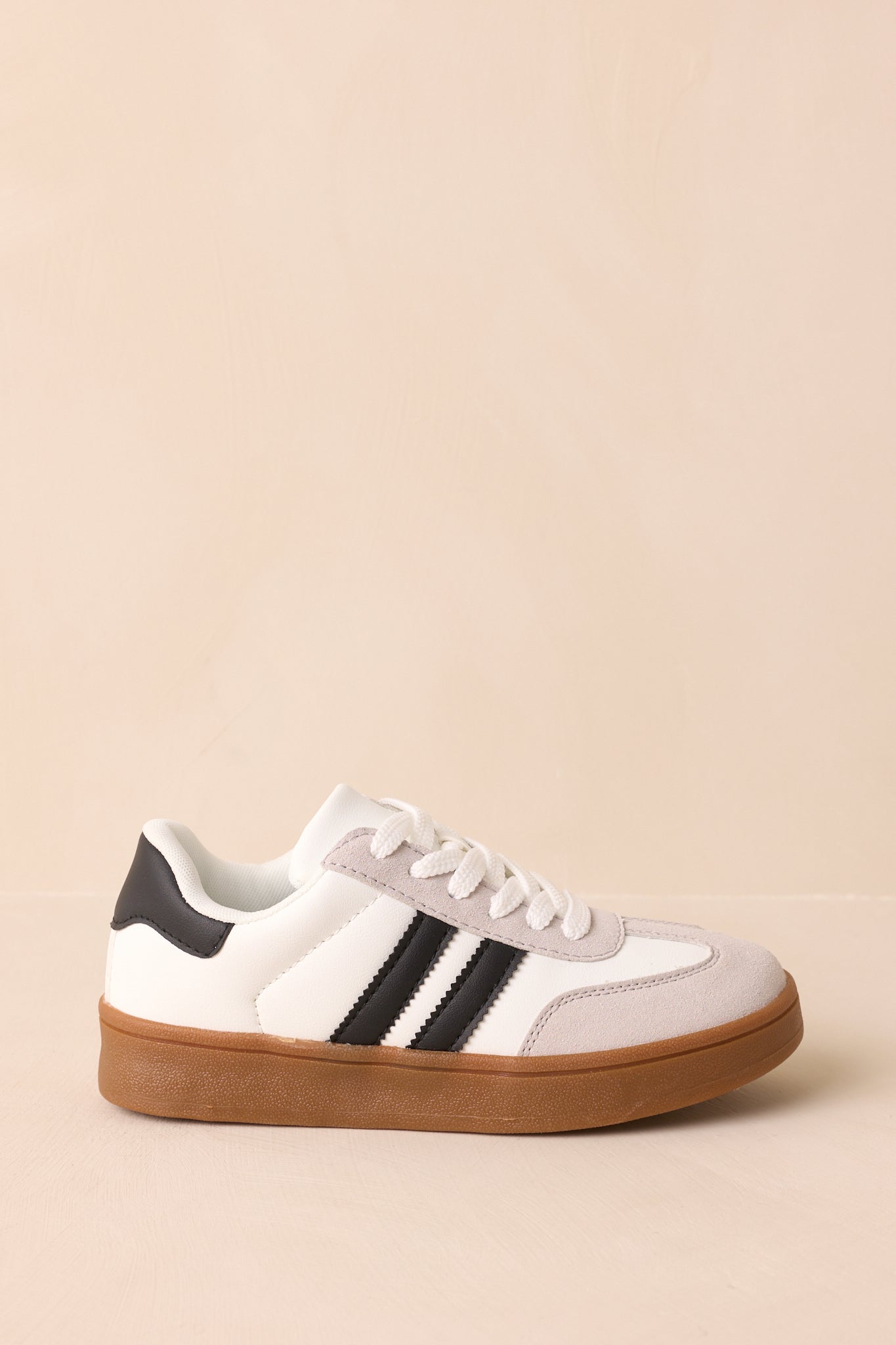Side view of the white faux leather and suede sneaker with smooth synthetic panels, black contrast stripes, and a gum rubber sole.