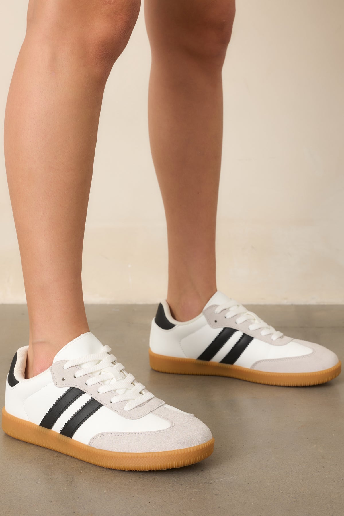 Detailed view of the sneaker's padded collar, rounded toe, white faux suede panels, and black side stripe accents.