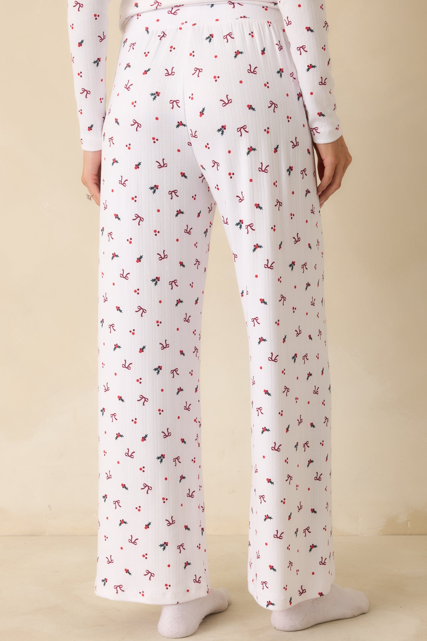 Back view of white full-length pants, displaying the wide-leg silhouette, high-rise elastic waistband, and allover holiday print.