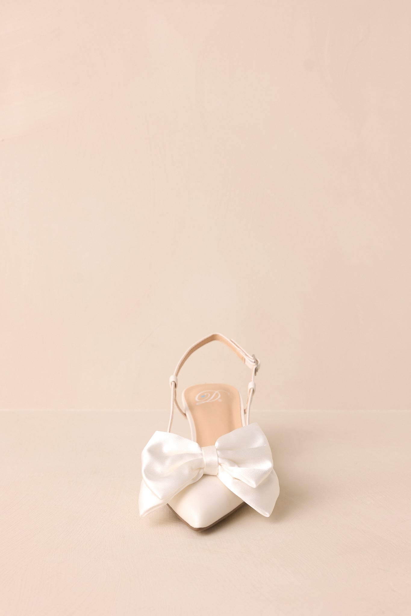 A timeless white heel with a pointed toe, accented by a soft satin bow for a touch of elegance.