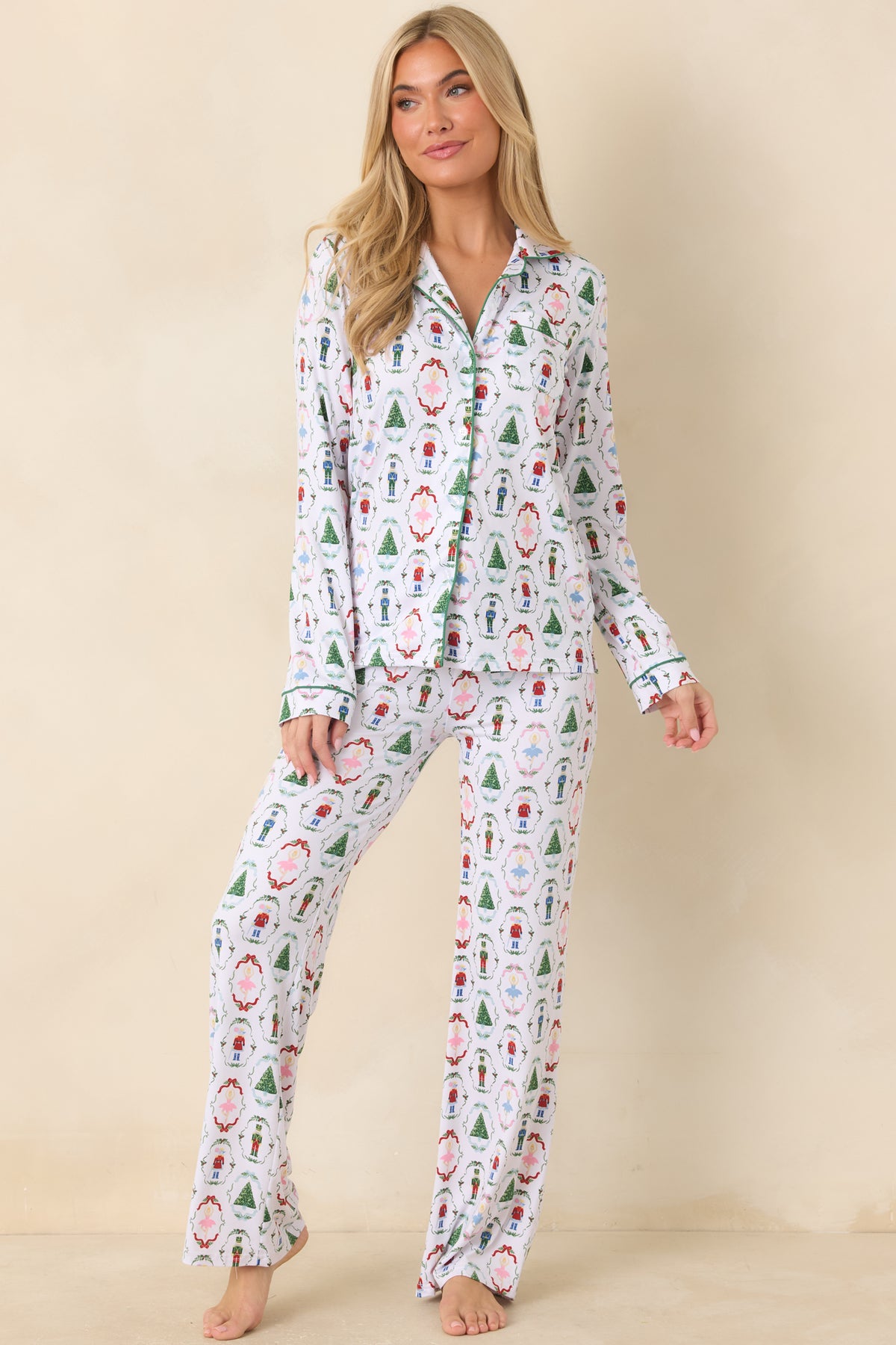 White woven pajama pants showcase a festive nutcracker pattern with contrasting green piping along the edges.