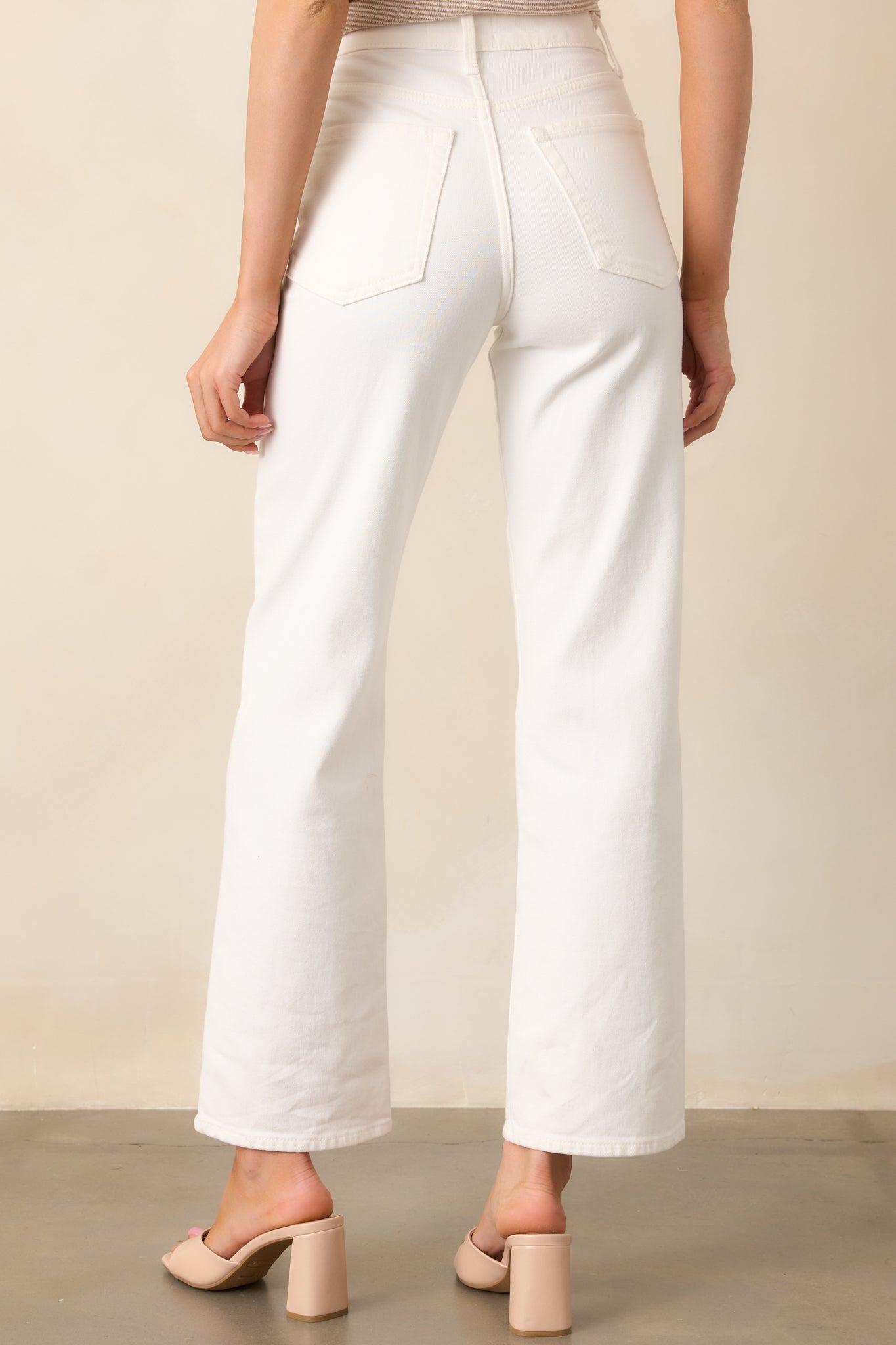 The white jeans viewed from behind, displaying the high-waisted fit, back pockets, and belt loops.