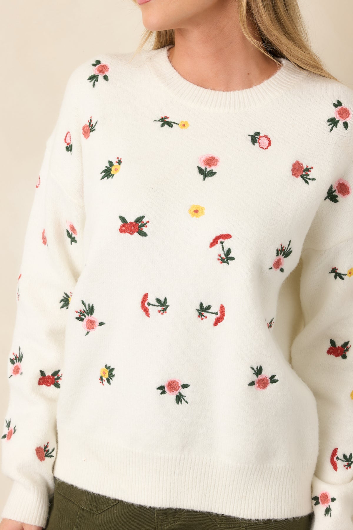 Close-up highlights the multicolor floral embroidery, textured white knit, crew neckline, and ribbed trim.