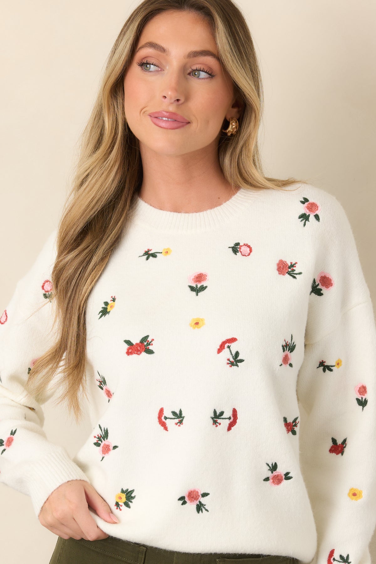 Detailed view showcases the vibrant floral embroidery and ribbed texture along the white knit sweater.