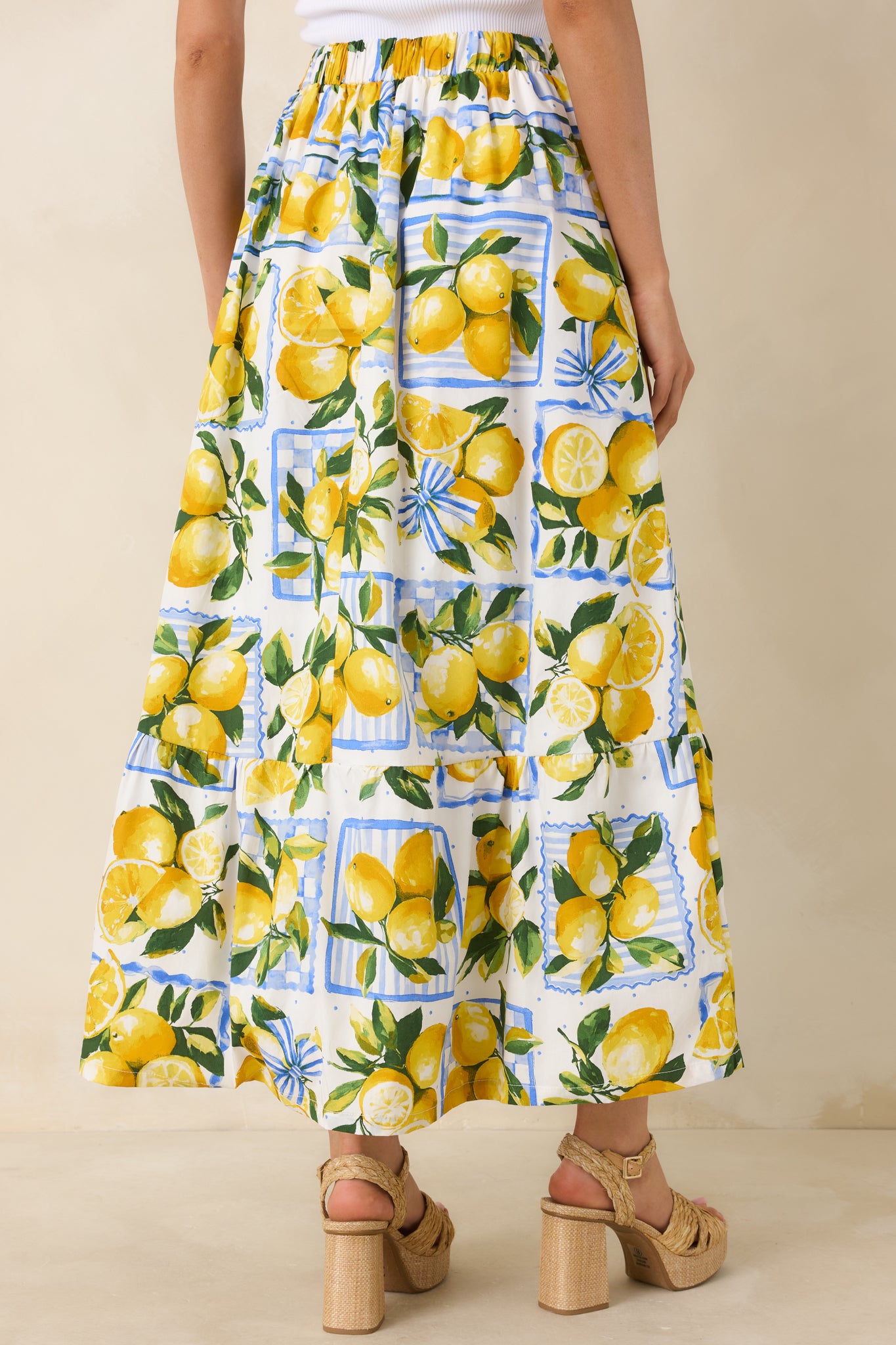 Rear view of the white lemon print midi skirt featuring elastic waistband, tiered panels, and a flowing ankle-length silhouette.