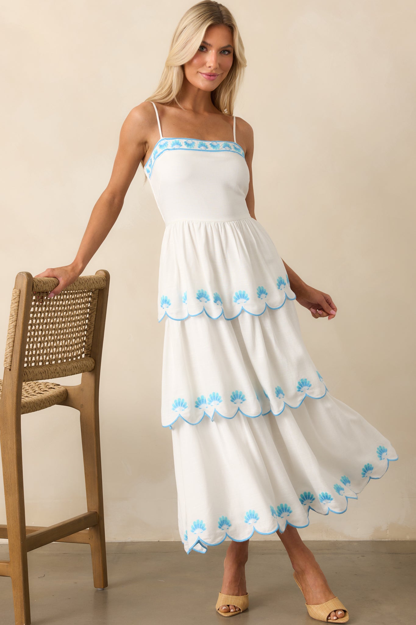 Front view of a white maxi dress featuring blue embroidered scallop shell details and a fitted bodice.
