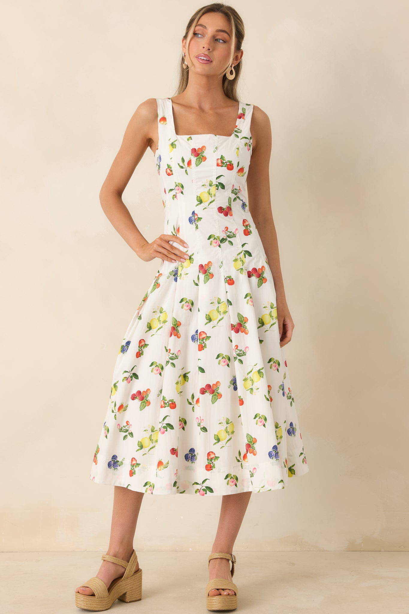 White midi dress with vibrant fruit pattern, structured bodice, and flowing skirt