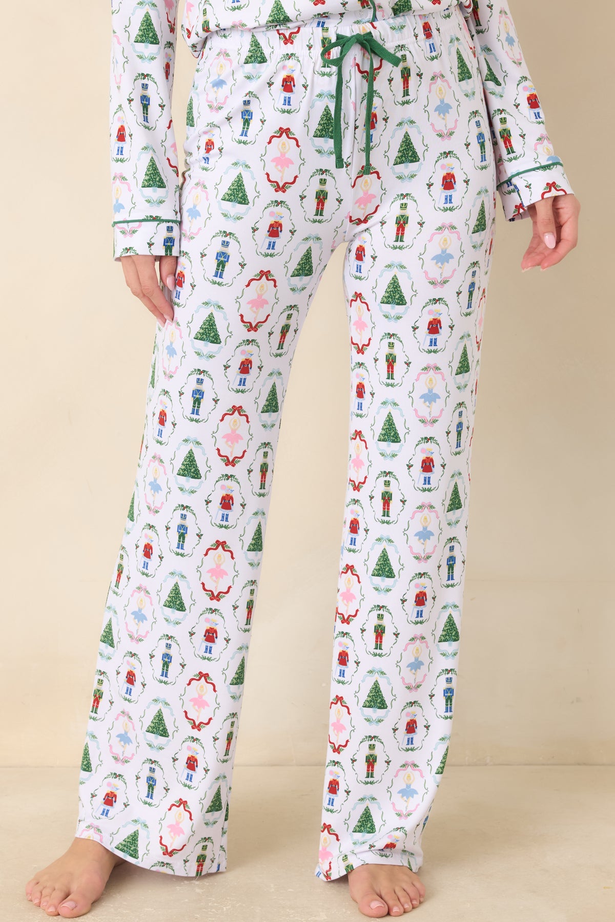 White pajama pants display the repeating nutcracker and holiday print across the front with a relaxed fit.