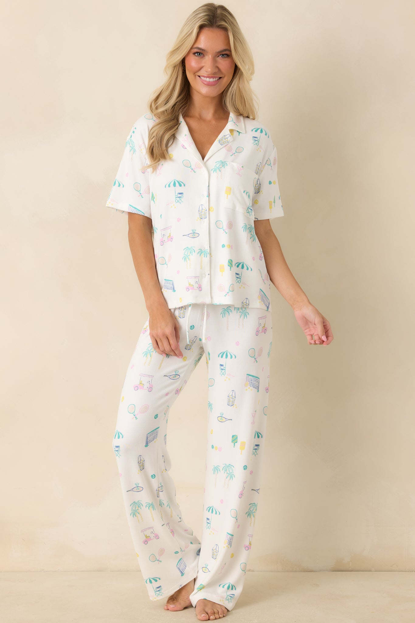 White pajama pants featuring an ultra-soft knit fabric, relaxed wide-leg silhouette, colorful court sports-inspired print, and elastic waistband.