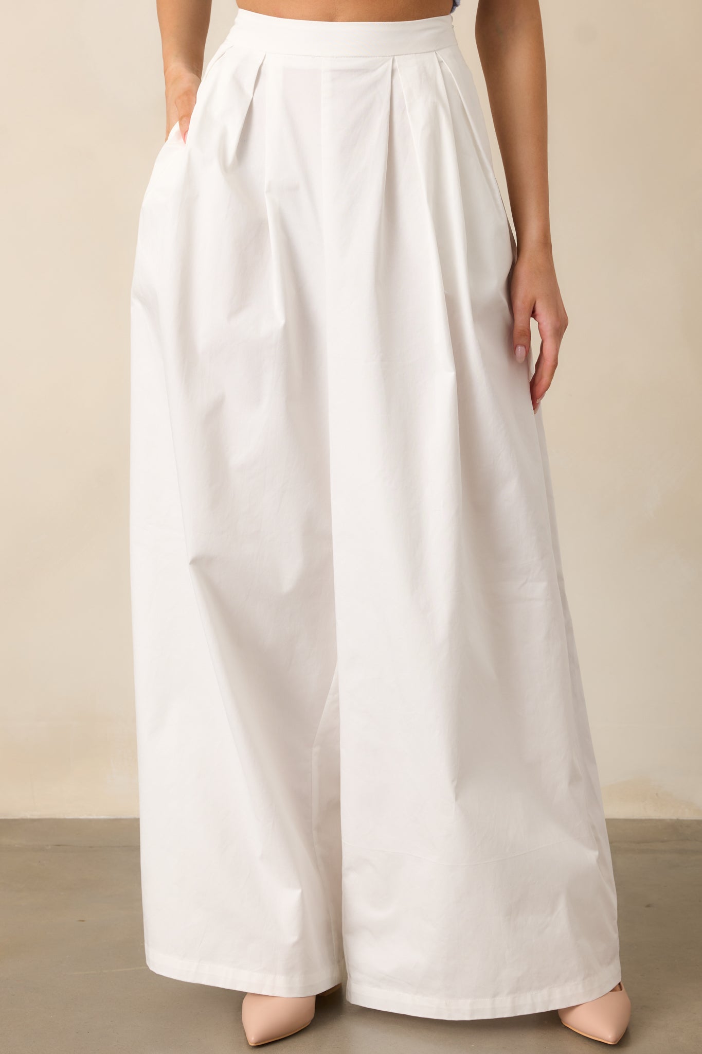 A closer view of the white pants, highlighting the high-waisted fit and subtle pleats for a tailored look.