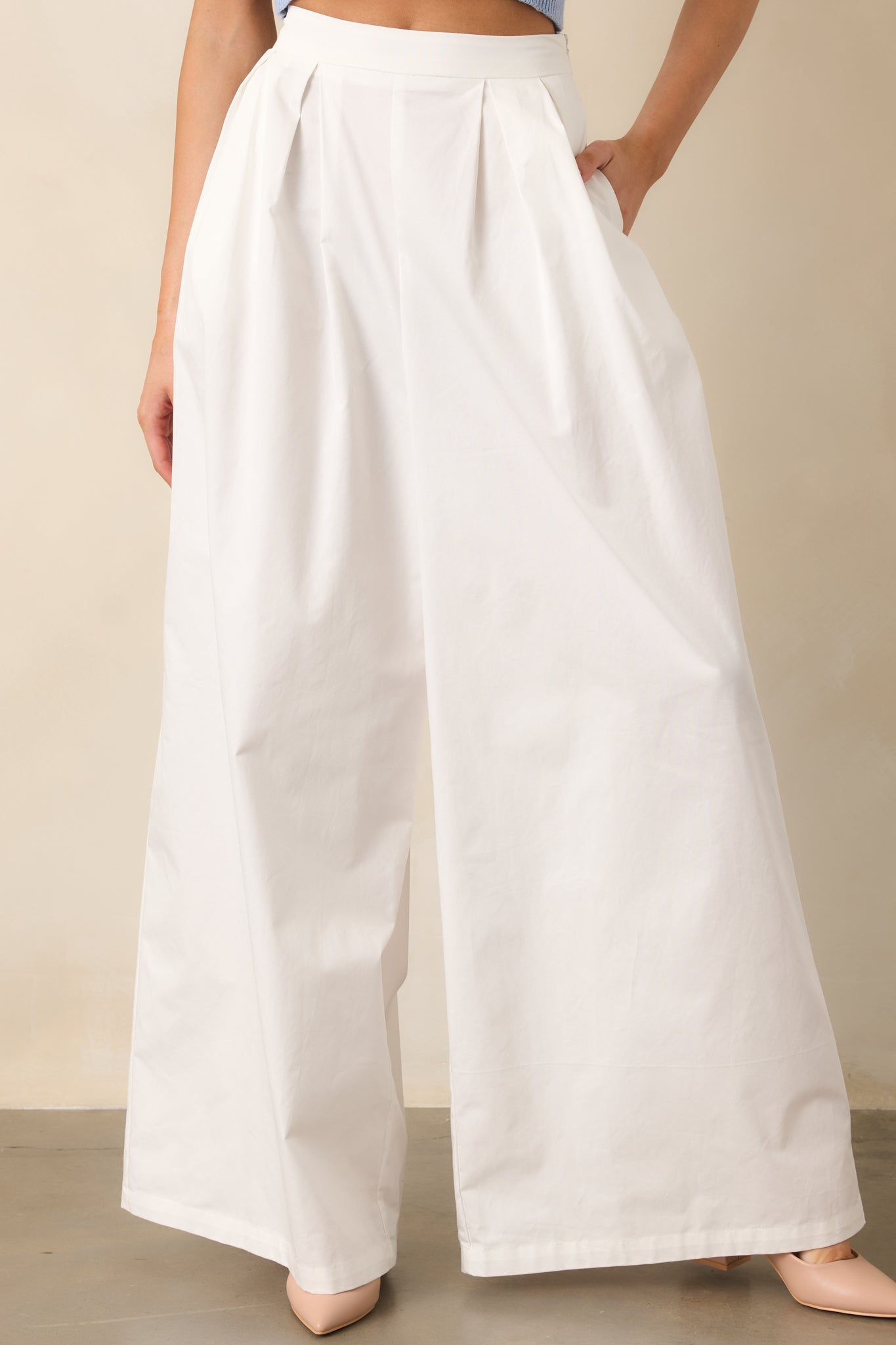 A zoomed-in shot of the pleated detailing and functional pocket of the white pants, emphasizing the refined construction.