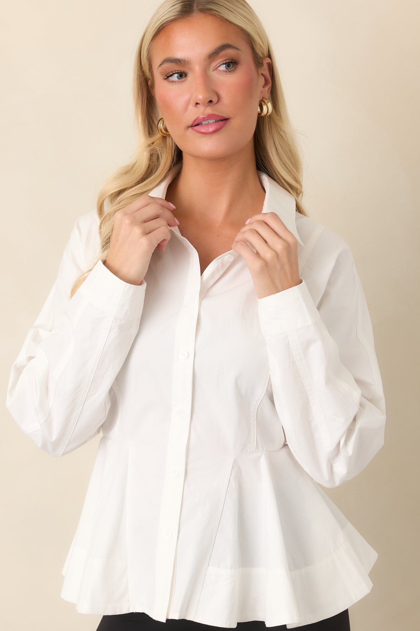 White peplum top highlighting the crisp collar, front buttons, and contoured waist seams.