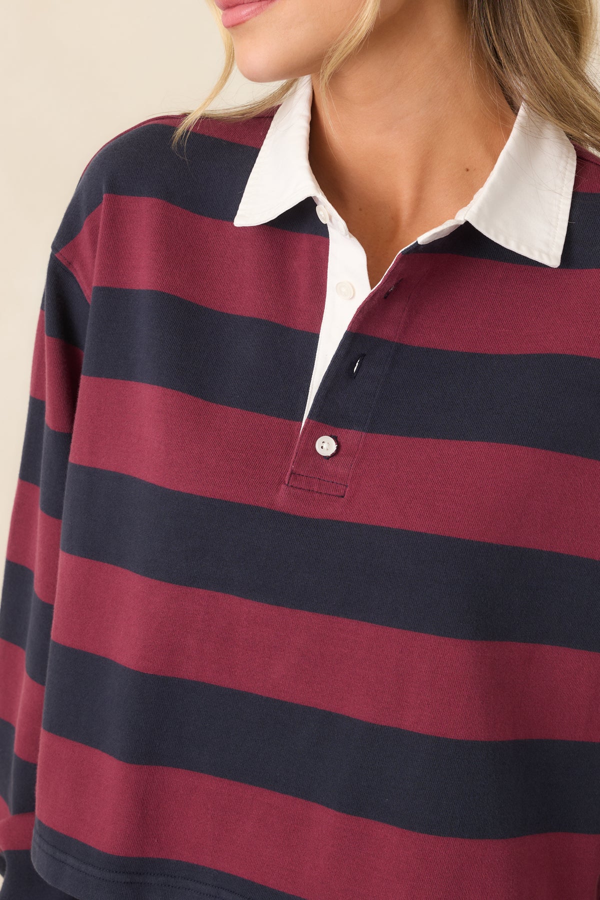 Close-up of the contrasting white point collar and partial button placket on the striped rugby polo top.