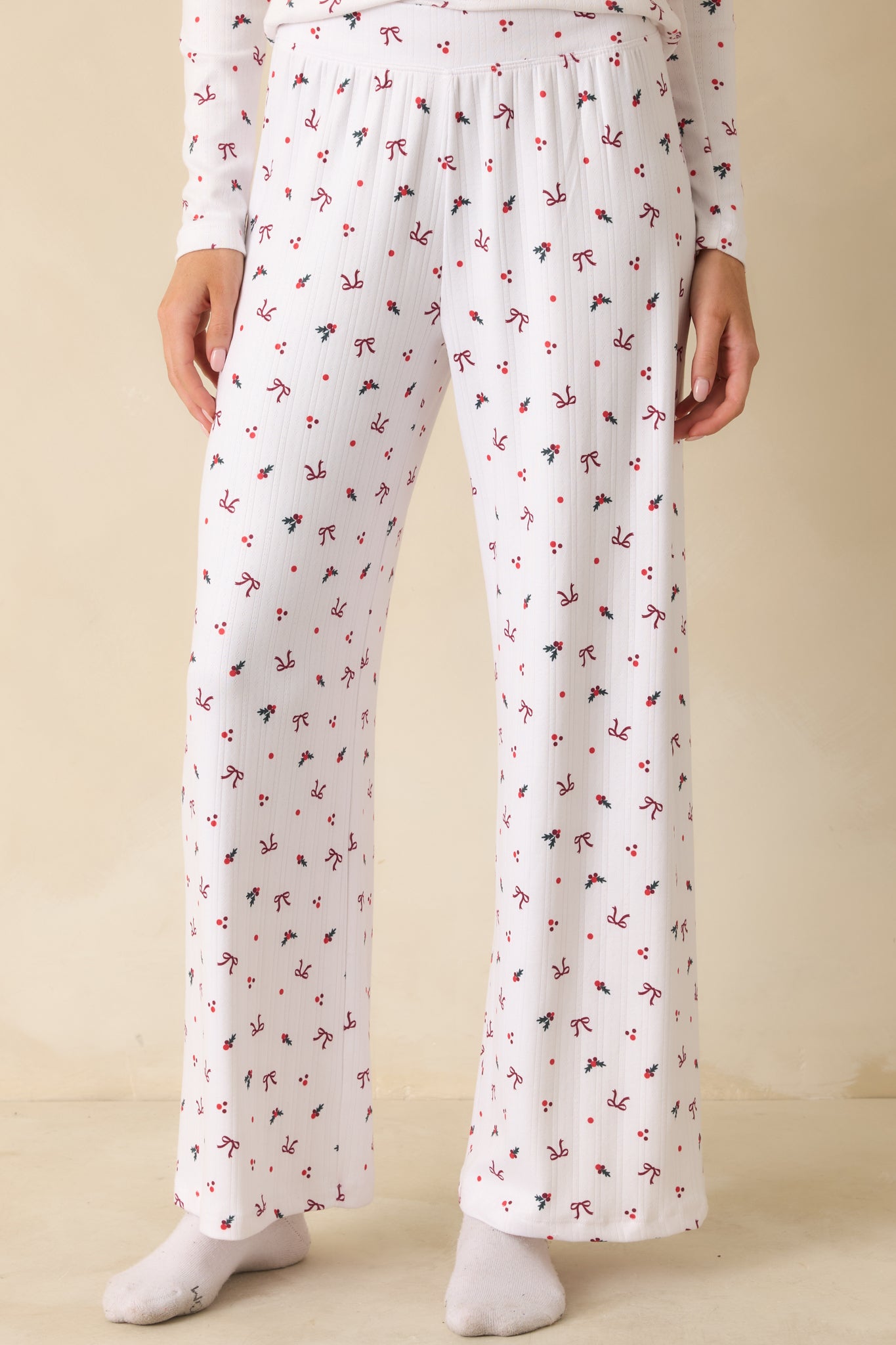 Detail of the front of white Pointelle pants, emphasizing the festive holly-and-bow pattern and smooth soft-wash finish.
